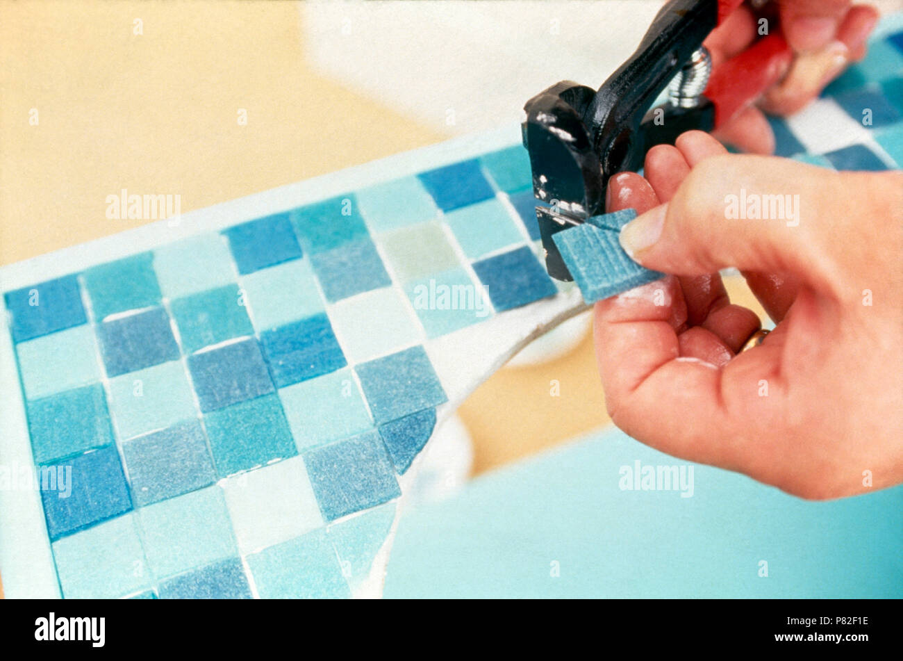 Nahaufnahme einer Hand schneiden Glas Mosaikfliesen auf einem Waschtisch anbringen Stockfoto