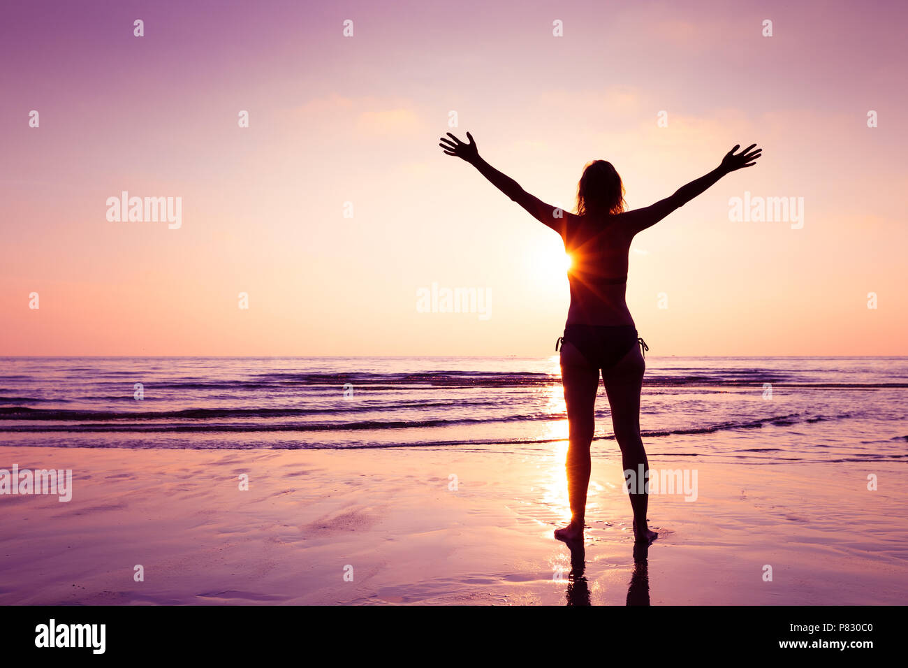 Gerne fröhliche Frau Verbreitung Hände am Strand bei Sonnenuntergang, freundliche Emotion und Achtsamkeit, Balance, eingedenk Denken Stockfoto