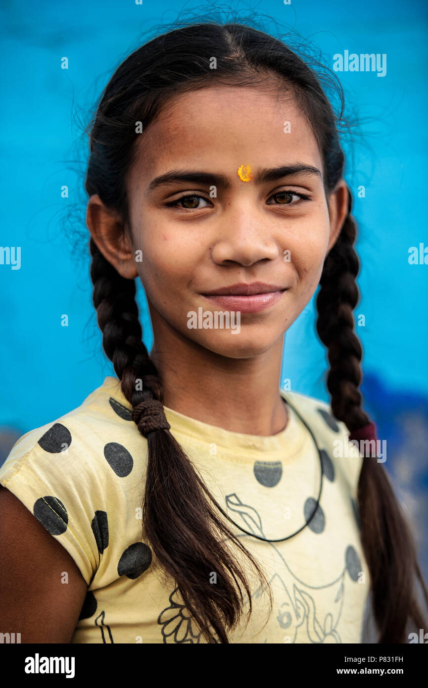 JODHPUR, Rajasthan - Indien - 12. Dezember 2017. Porträt einer wunderschönen und lächelnd Indisches Kind mit ihrem Haar zu Zöpfen gesammelt und einem blauen backgroun Stockfoto