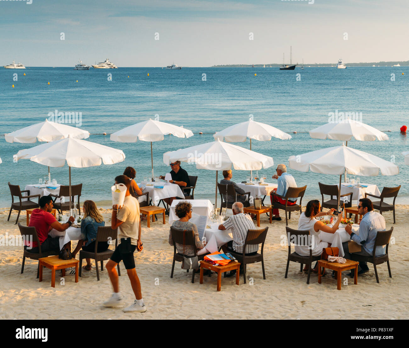 Juan-les-Pins, Frankreich - Juli 7., 2018: Paare haben Getränke und Häppchen in einem luxuriösen Restaurant am Strand an der französischen Riviera Resort Stadt Stockfoto