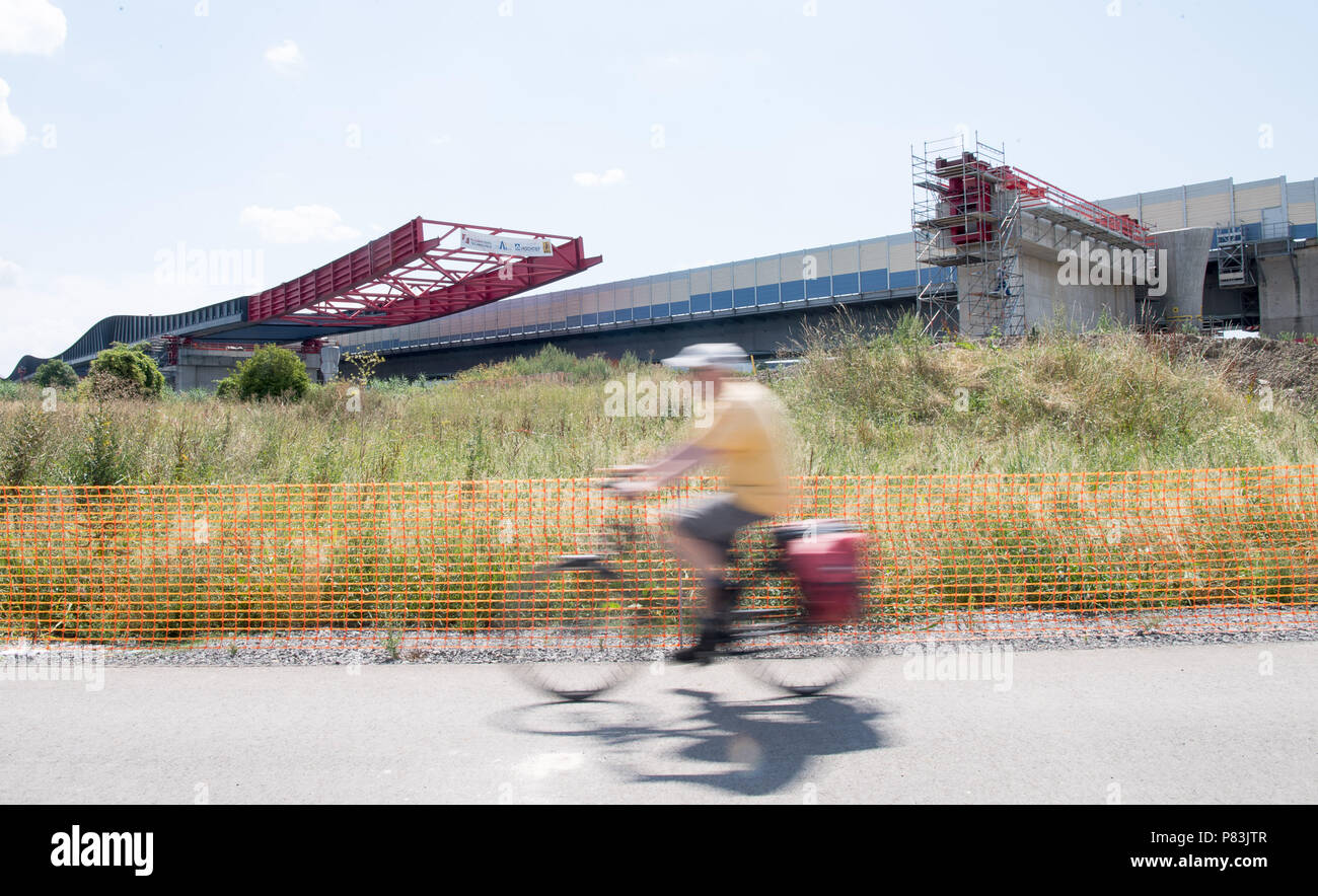 09. Juli 2018, Deutschland, Heilbronn: ein Radfahrer an einer Autobahn Brücke, die über dem Neckar geschoben (Wirkung Durch lange Exposition). Die Autobahn A6 wird auf sechs Fahrspuren, erfordert eine neue Brücke erweitert. Die Konstruktion wiegt 4000 Tonnen und wird mit einer Geschwindigkeit von 12 Metern pro Stunde auf einer Strecke von 130 Meter geschoben. Es soll vorläufig ab 2019 ff. für die Bundesgartenschau verwendet werden. Foto: Sebastian Gollnow/dpa Stockfoto