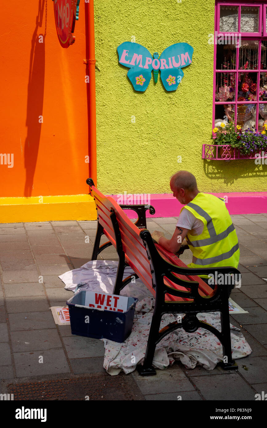 Ein Stadtrat malt die Straßenbank in leuchtenden Farben in der Market Lane im Stadtzentrum von Kinsale, County Cork, Irland. Stockfoto