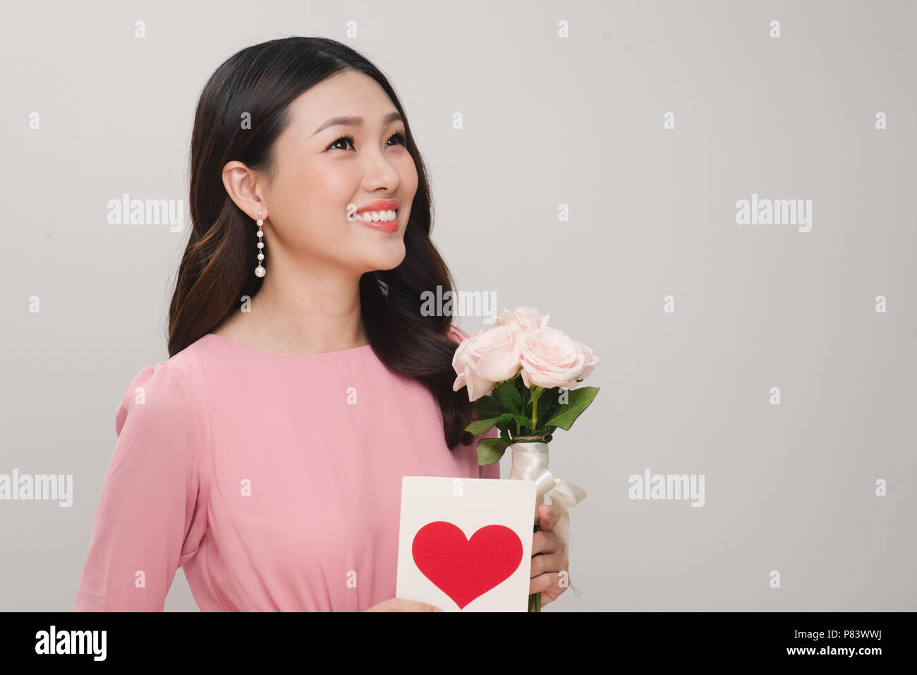 Junge schöne lächelnde Frau mit Blumenstrauß aus wunderschönen Rosen Blumen, Postkarte auf weißem Hintergrund. St. Valentines Tag oder Internationalen W Stockfoto