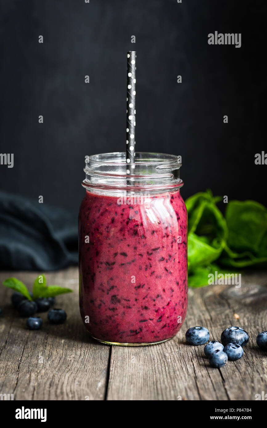 Frische acai blueberry Smoothie in der Flasche auf Holztisch auf schwarzen Hintergrund. Detailansicht, selektive konzentrieren. Konzept der gesunden Lebensweise, gesunde ea Stockfoto
