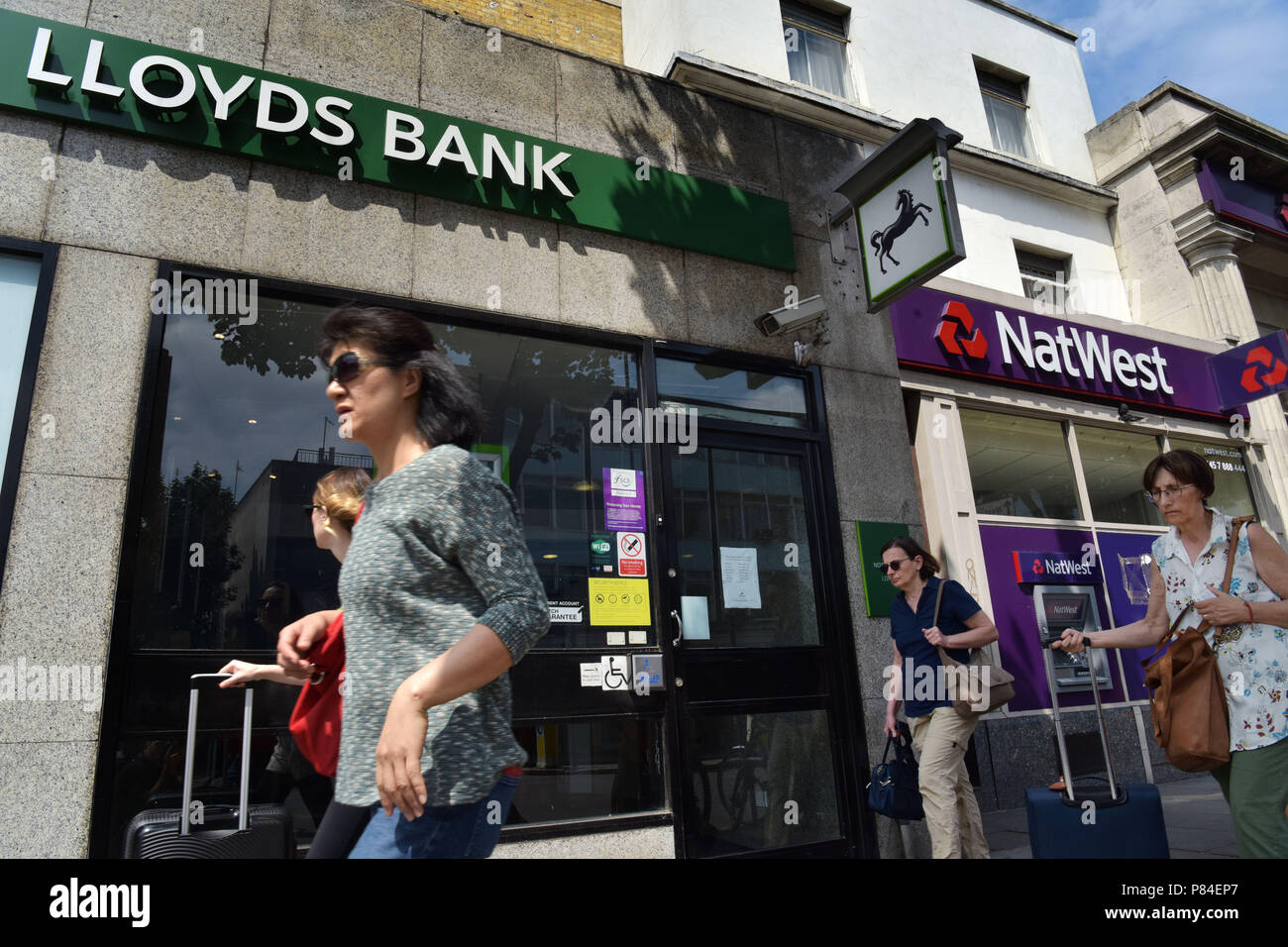 Menschen gehen vorbei an den Zweigen der NatWest und Lloyds Banken in Notting Hill London Stockfoto