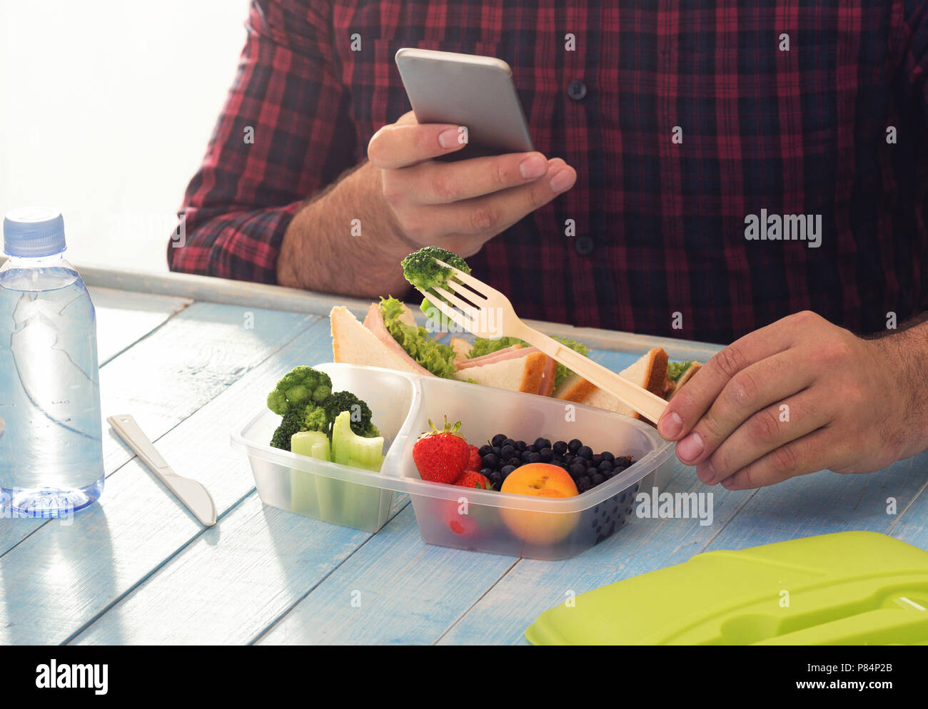 Mann fotografieren Lunch Box mit gesunden Lebensmitteln am blauen Tisch sitzen. Gesunde Ernährung Konzept Stockfoto