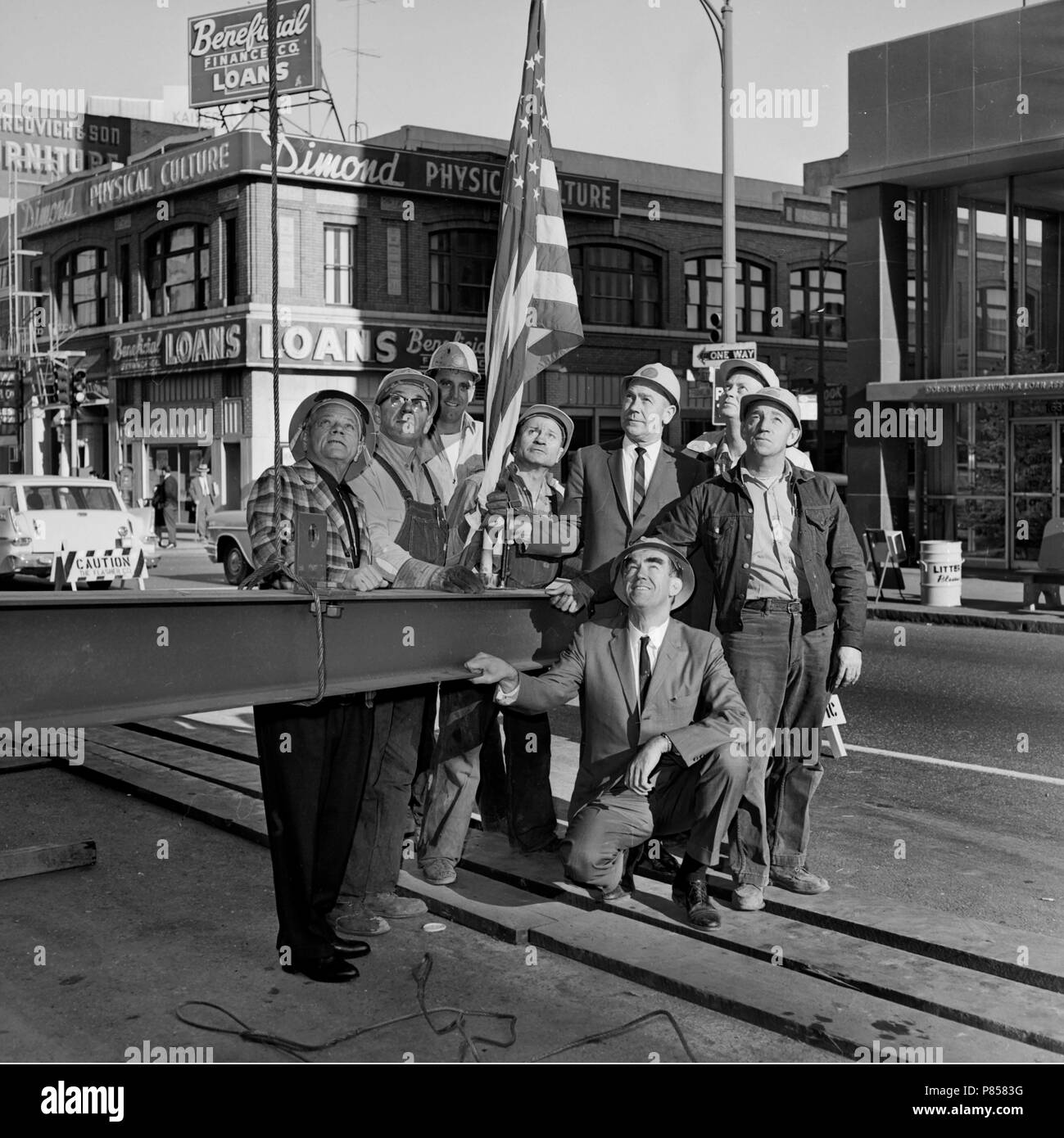 Arbeitnehmer und Führungskräfte zusehen, wie der letzte Lichtstrahl, der Innenstadt von Kansas City, Missouri Gebäude ist Gehisst, Ca. 1965. Stockfoto