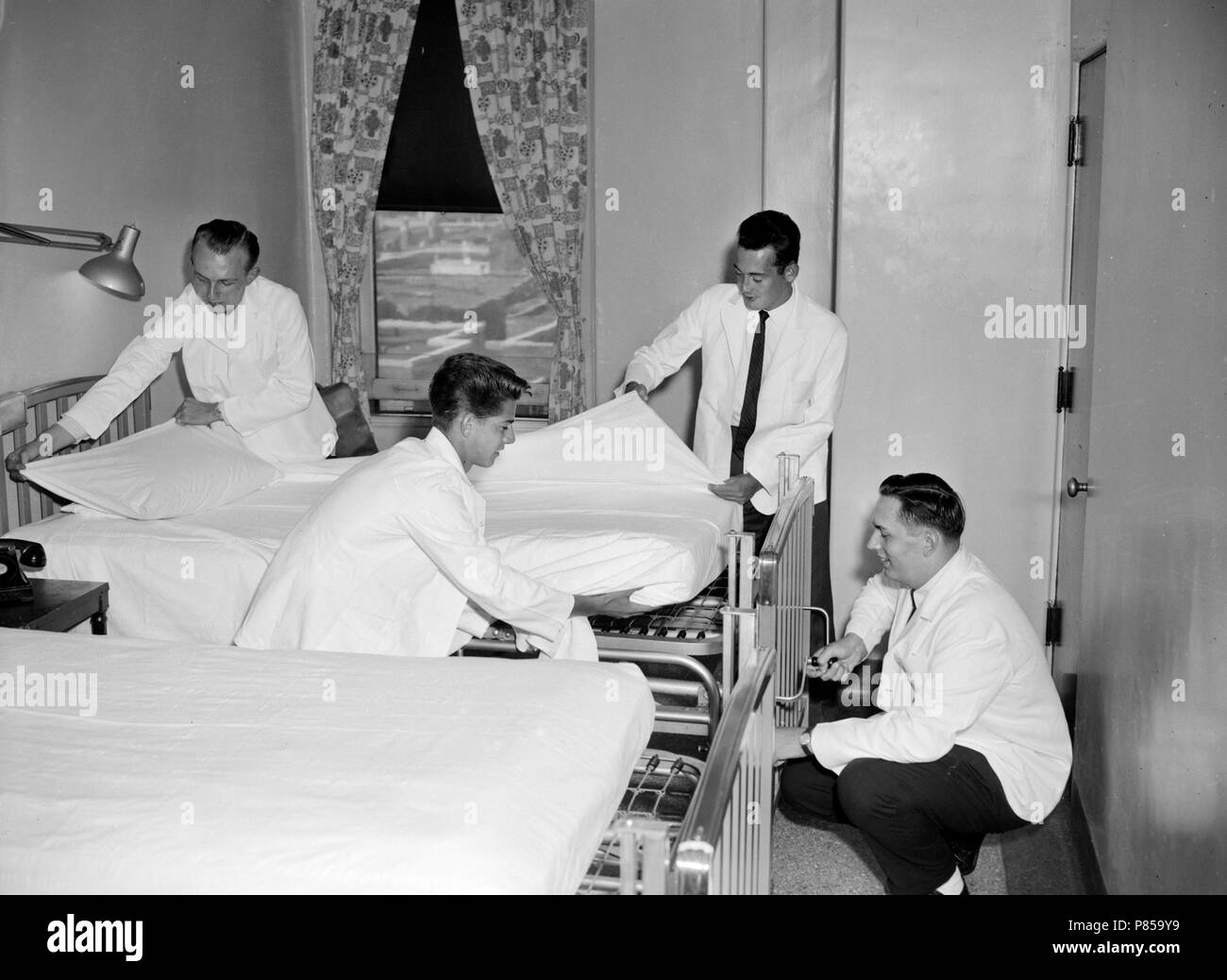 Männliche Kursteilnehmer Krankenschwestern Make-up Betten in einer Krankenpflegeschule in Kalifornien, Ca. 1957. Stockfoto