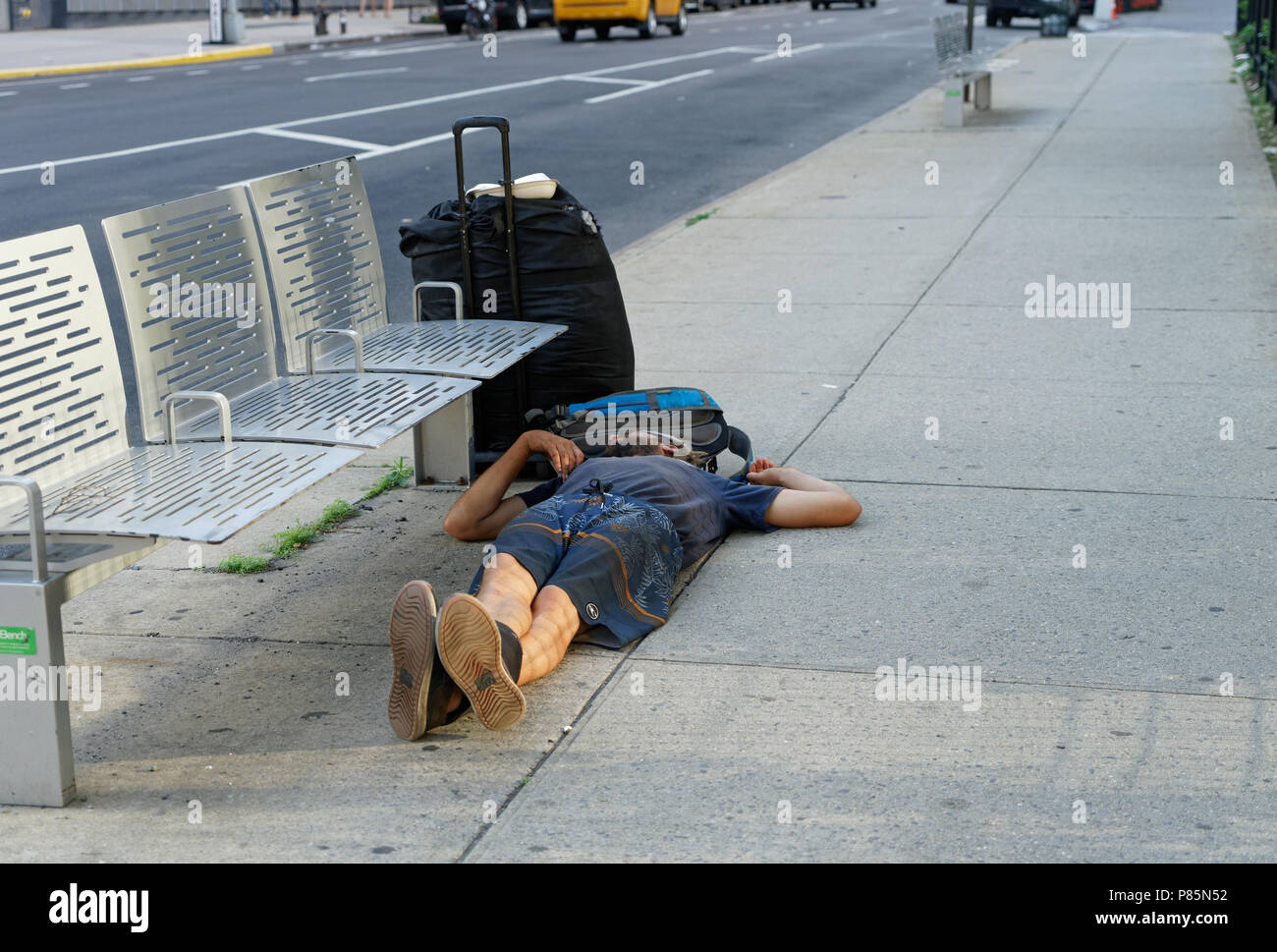 Ein obdachloser Mann schlief auf dem Bürgersteig neben seinen Koffer und Rucksack auf die Hudson Street in Lower Manhattan. Stockfoto