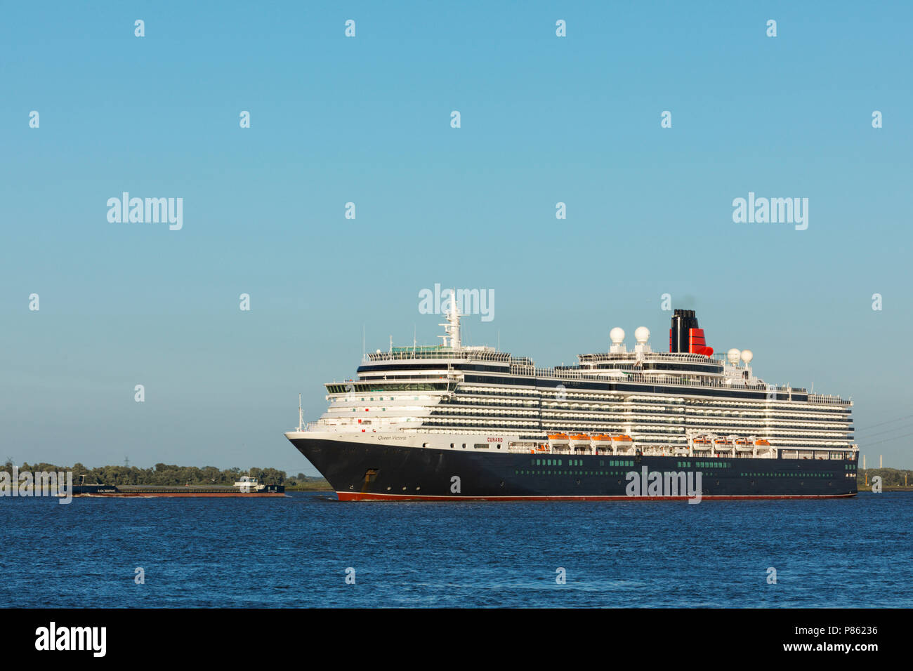 Kreuzfahrt Schiff HMS Queen Victoria, von Cunard Linien betrieben, vorbei an einem großen Schiff auf der Elbe in der Nähe von Hamburg. Stockfoto