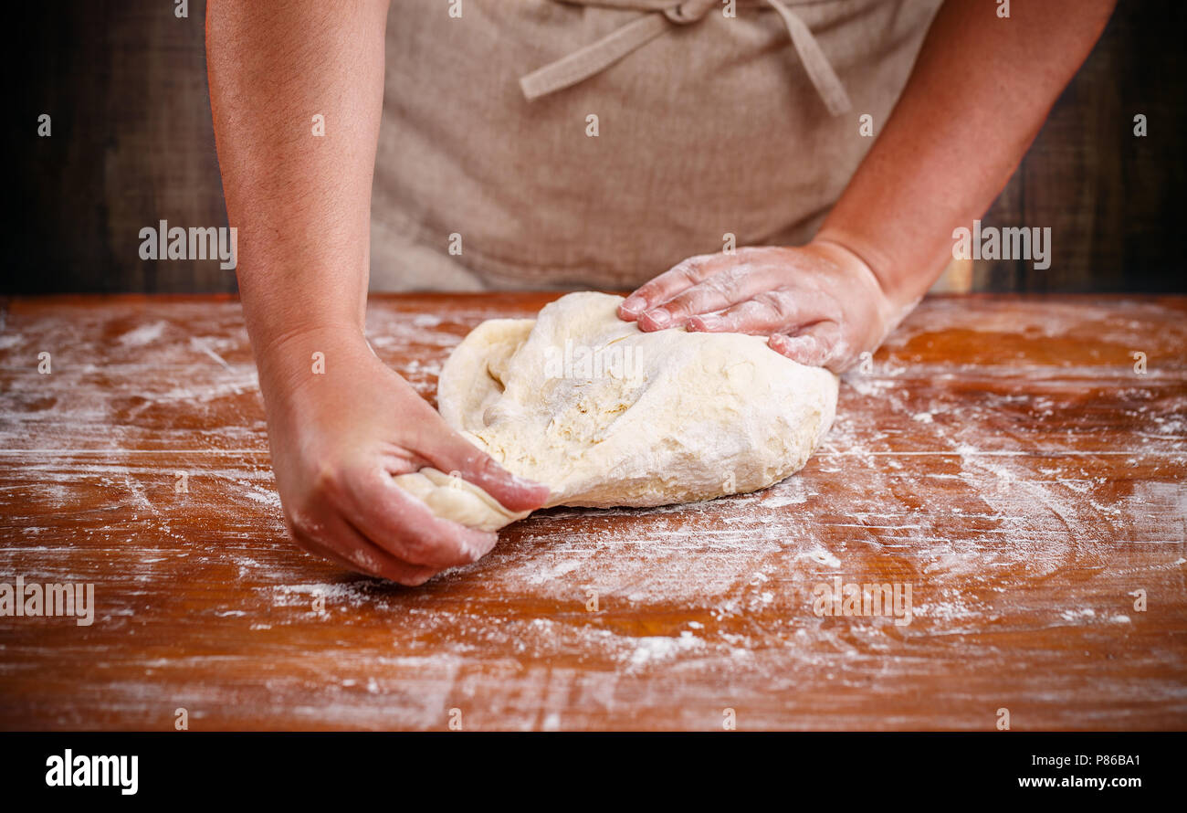 Weibliche Hände vorbereiten Teig für Pizza auf dem Tisch closeup Stockfoto