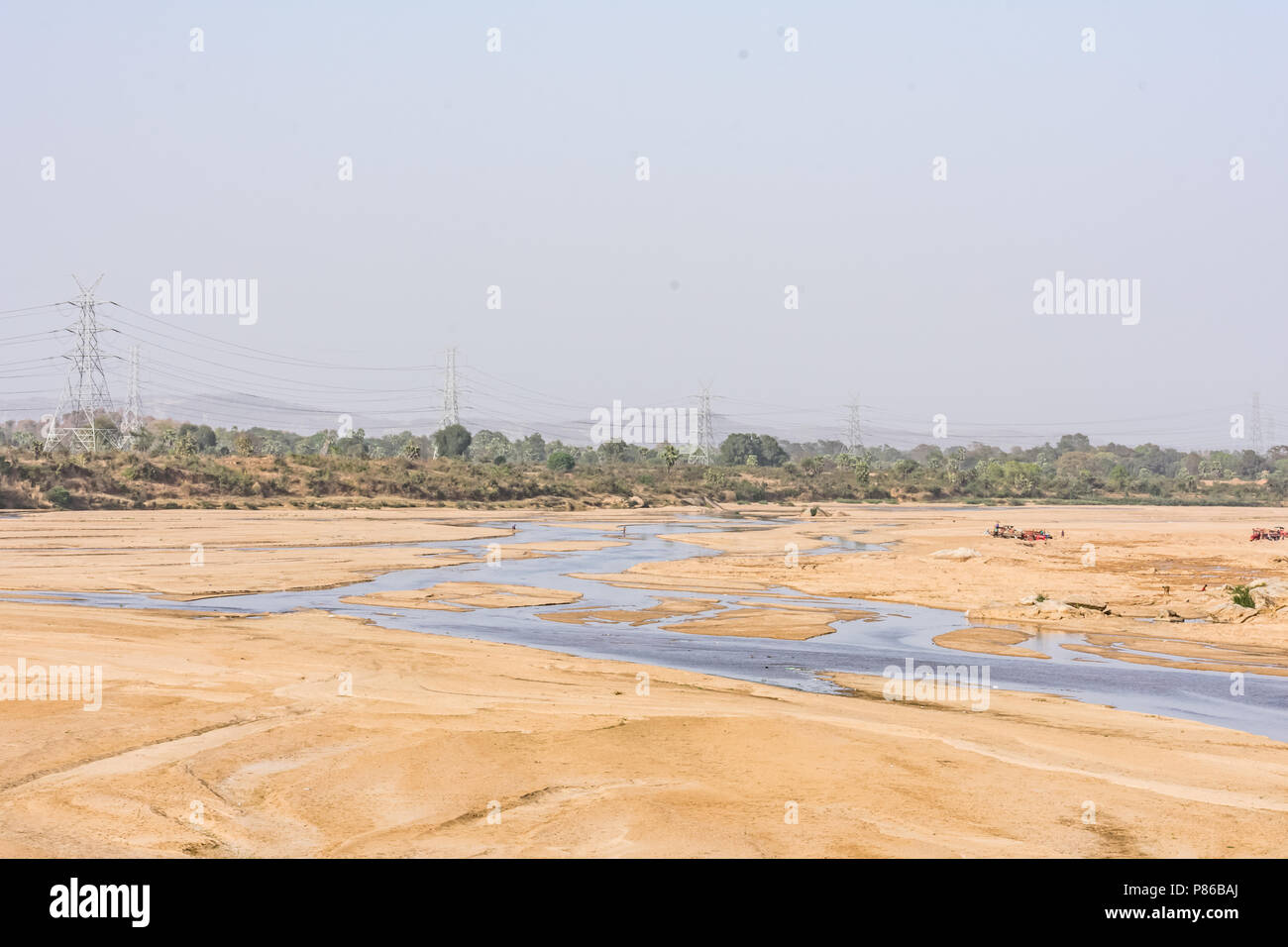 Indian River mit sauberem Wasser in sandigen Bett mit Power Grid Kabelverlegung Hintergrund. Stockfoto