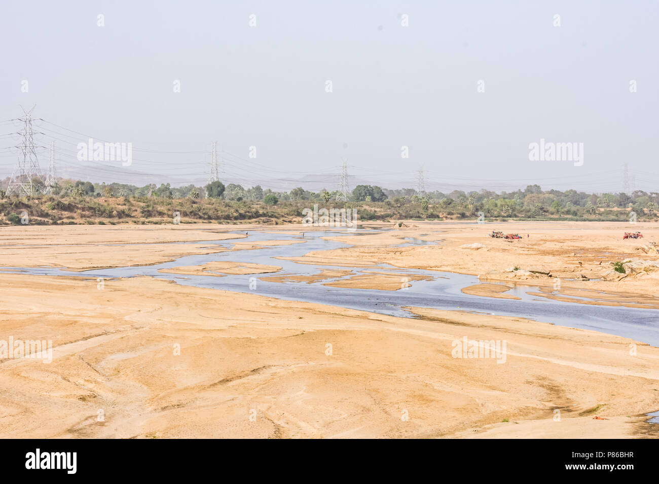 Indian River mit sauberem Wasser in sandigen Bett mit Power Grid Kabelverlegung Hintergrund. Stockfoto