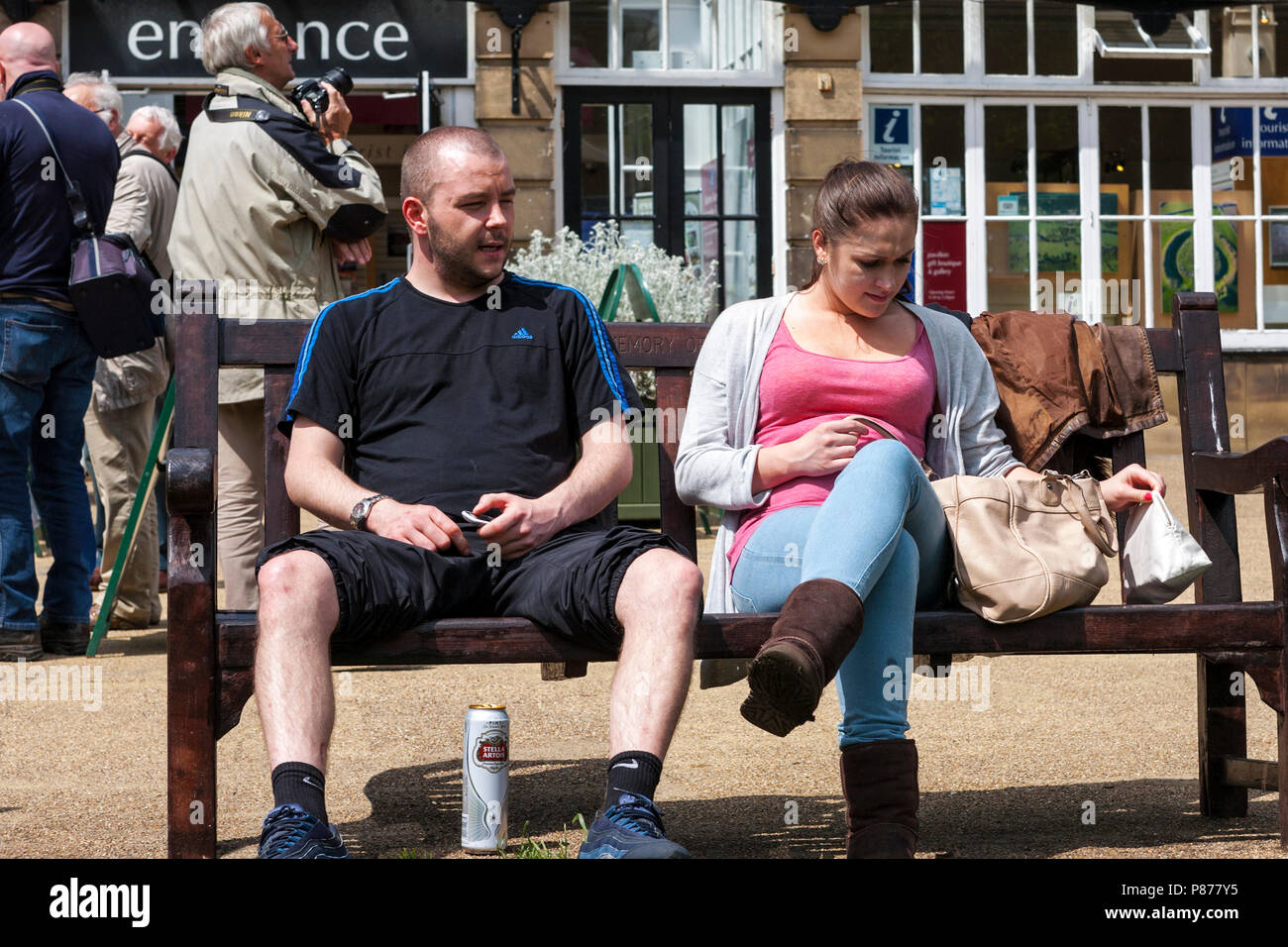 Paar sitzen auf einer Parkbank, mit Bier und Imbiss, Pavilion Gardens, Buxton, Derbyshire, England, Großbritannien Stockfoto