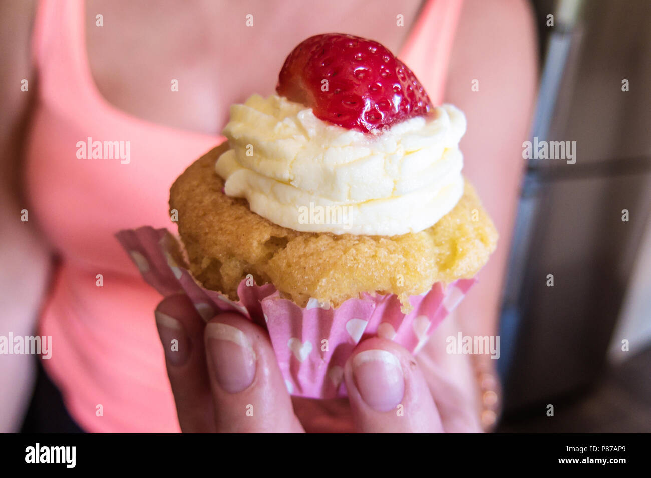 Nahaufnahme der Erdbeere Cupcake mit Butter Puderzucker in Lady's Hand Stockfoto