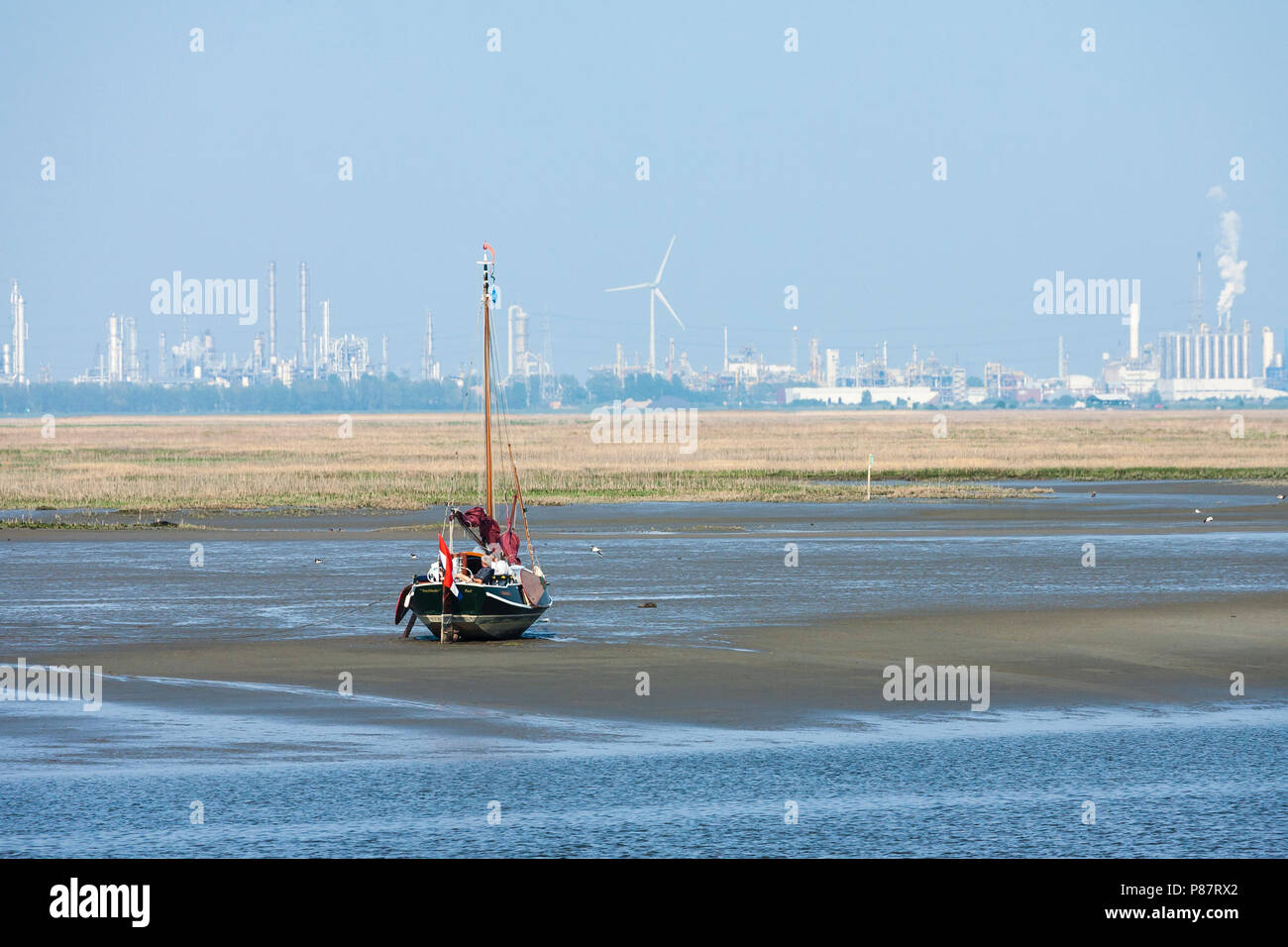 Boot bei Ebbe an ertrunken Land der Saeftinghe mit industriellen Bereich im Hintergrund Stockfoto