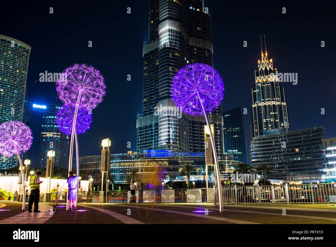 Dubai, Vereinigte Arabische Emirate - 18. Mai 2018: Burj Khailfa und Löwenzahn leuchtet auf einem Gehweg vor Dubai Mall bei Nacht Stockfoto