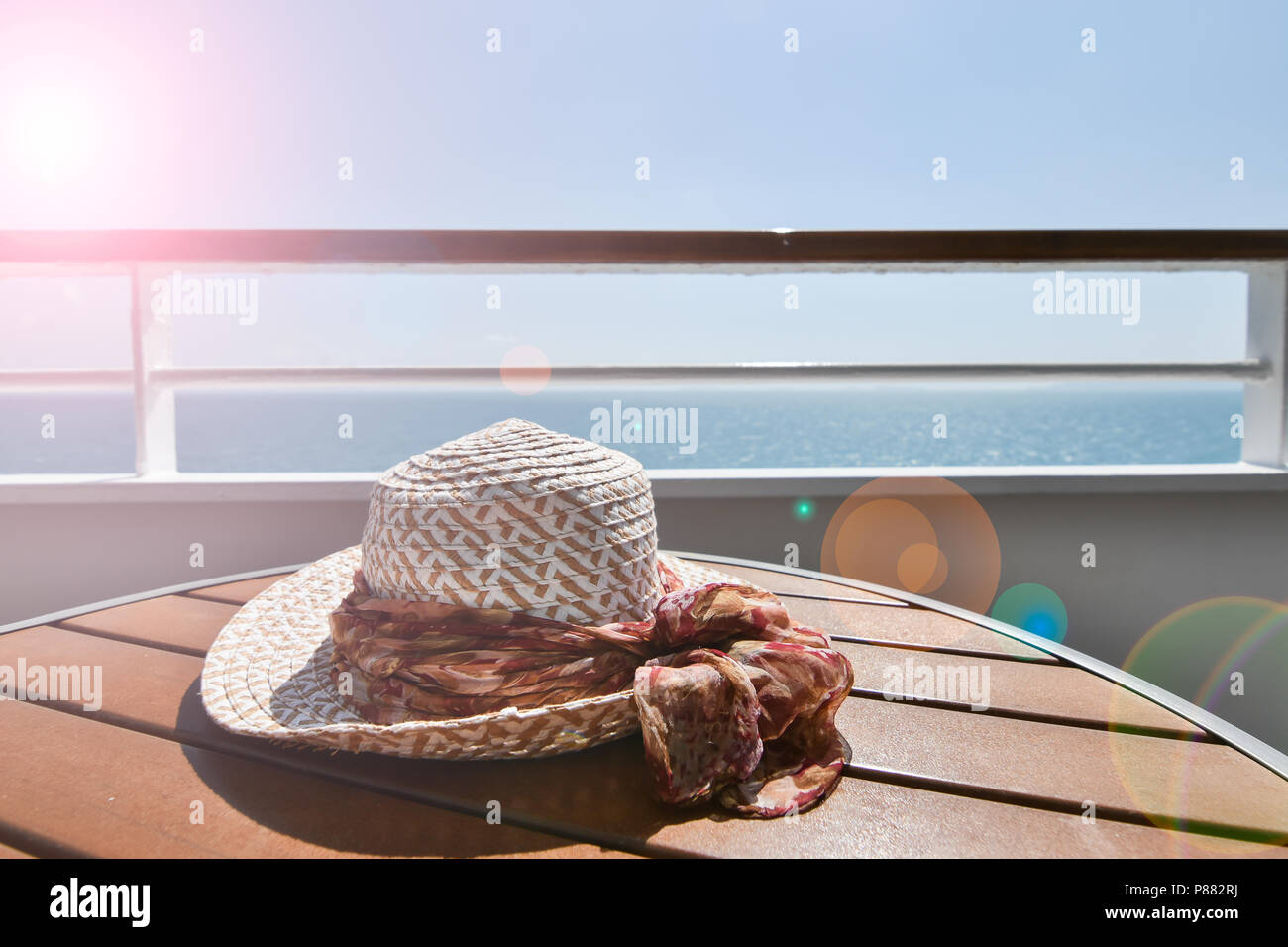Woman's Hut auf dem Balkon Tabelle der Kreuzfahrtschiffe. Sommer reisen Konzept mit Sun Flair. Stockfoto