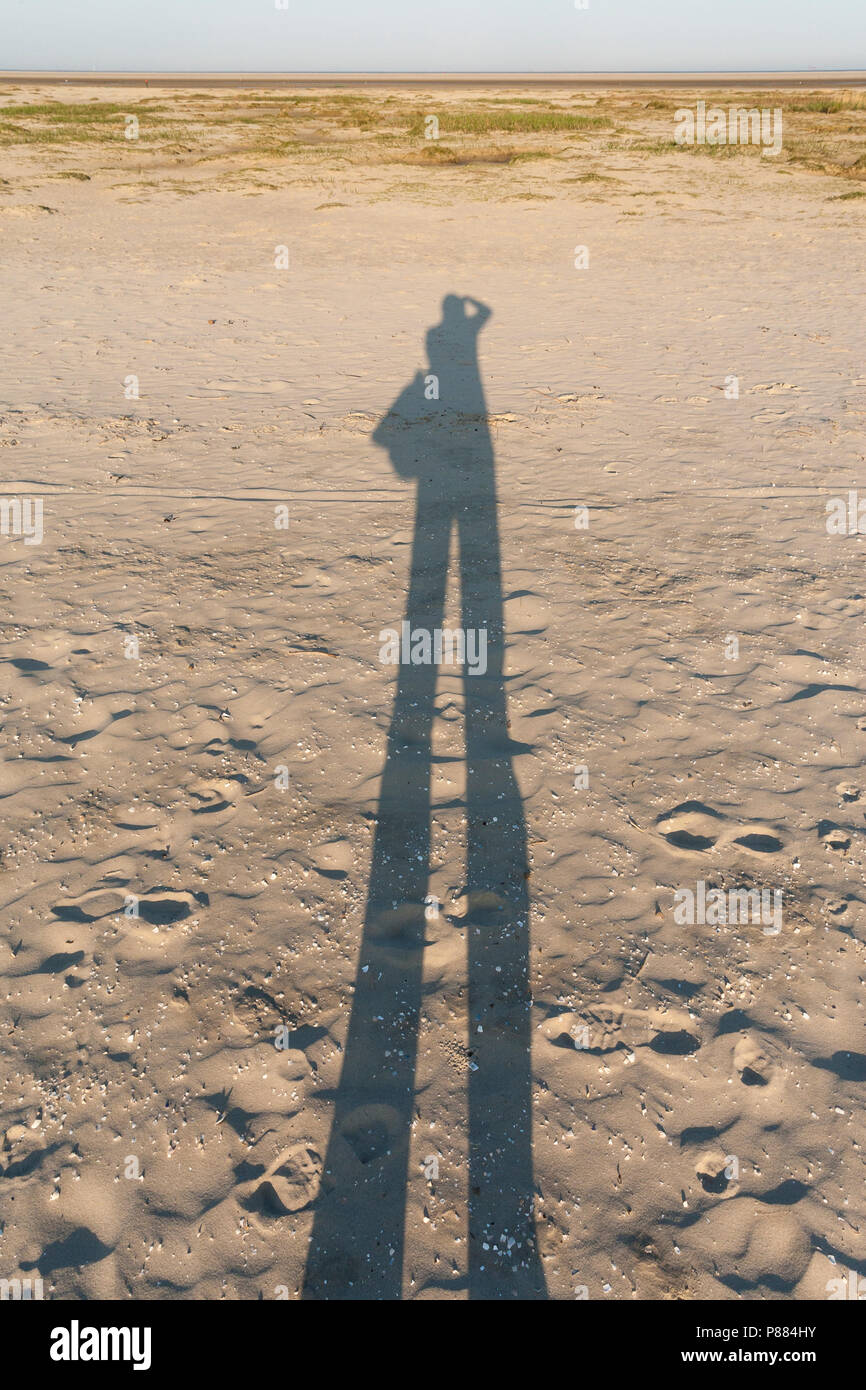 Sonnenschutz van fotograferende Mann op het Strand; Schatten fotografieren Mann am Strand Stockfoto