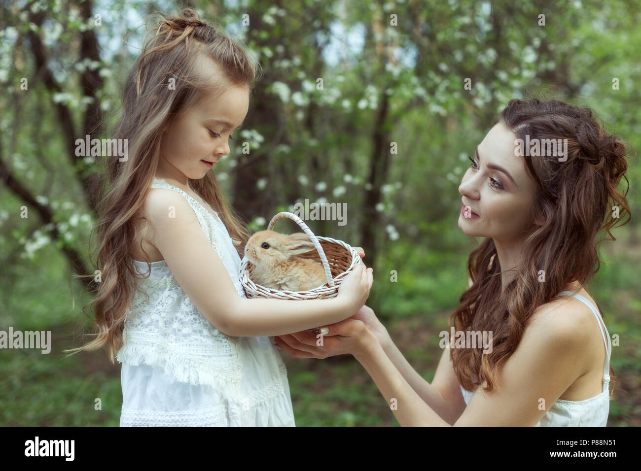 Portrait von Mutter und Tochter in den Wald. In den Händen der Mädchen ein Korb mit einem Kaninchen. Stockfoto