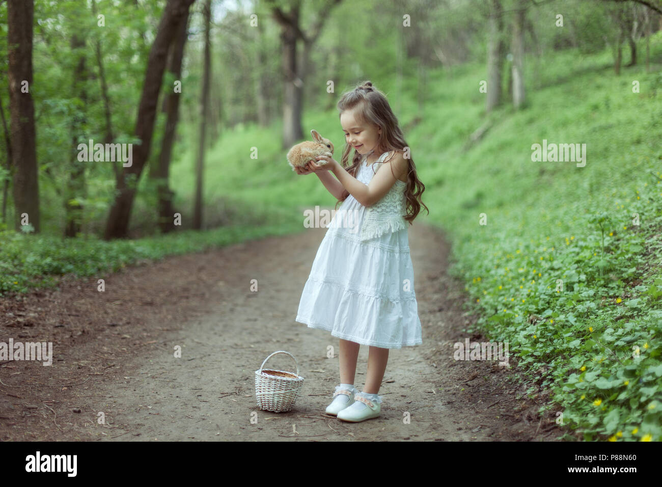Portrait von ein kleines Mädchen in einem Märchenwald. Sie hält ein kleines Kaninchen in ihren Händen. Stockfoto