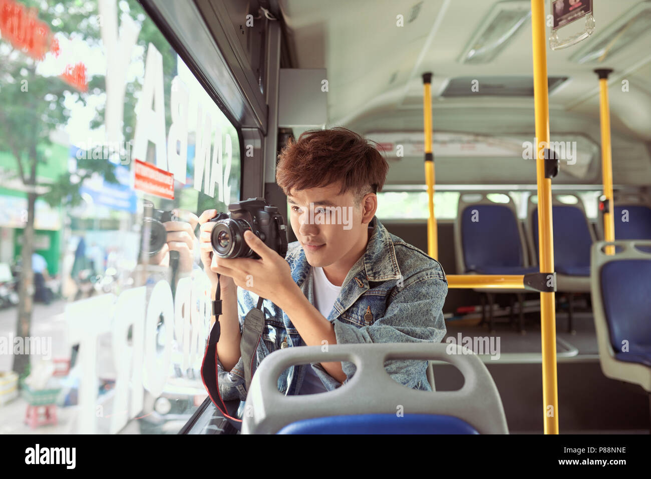Junge asiatischer Mann ein Foto im Bus mit Ihrer Digitalkamera Stockfoto