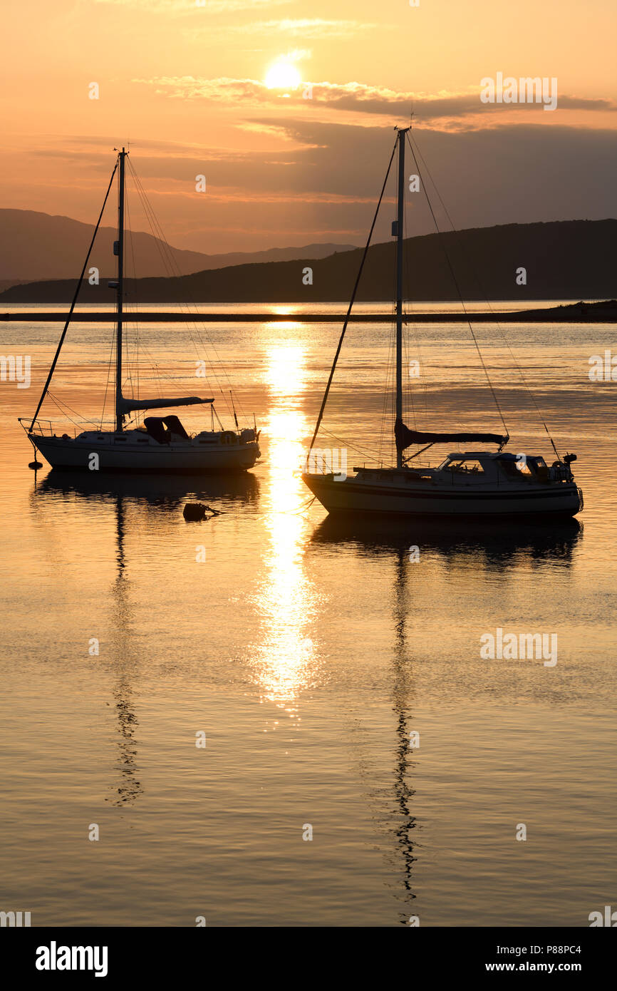 Volle Sonne auf dem Wasser von Ardmucknish Bucht im Norden Connel und Oban Airport widerspiegelt mit Segelbooten in Silhouette Stockfoto
