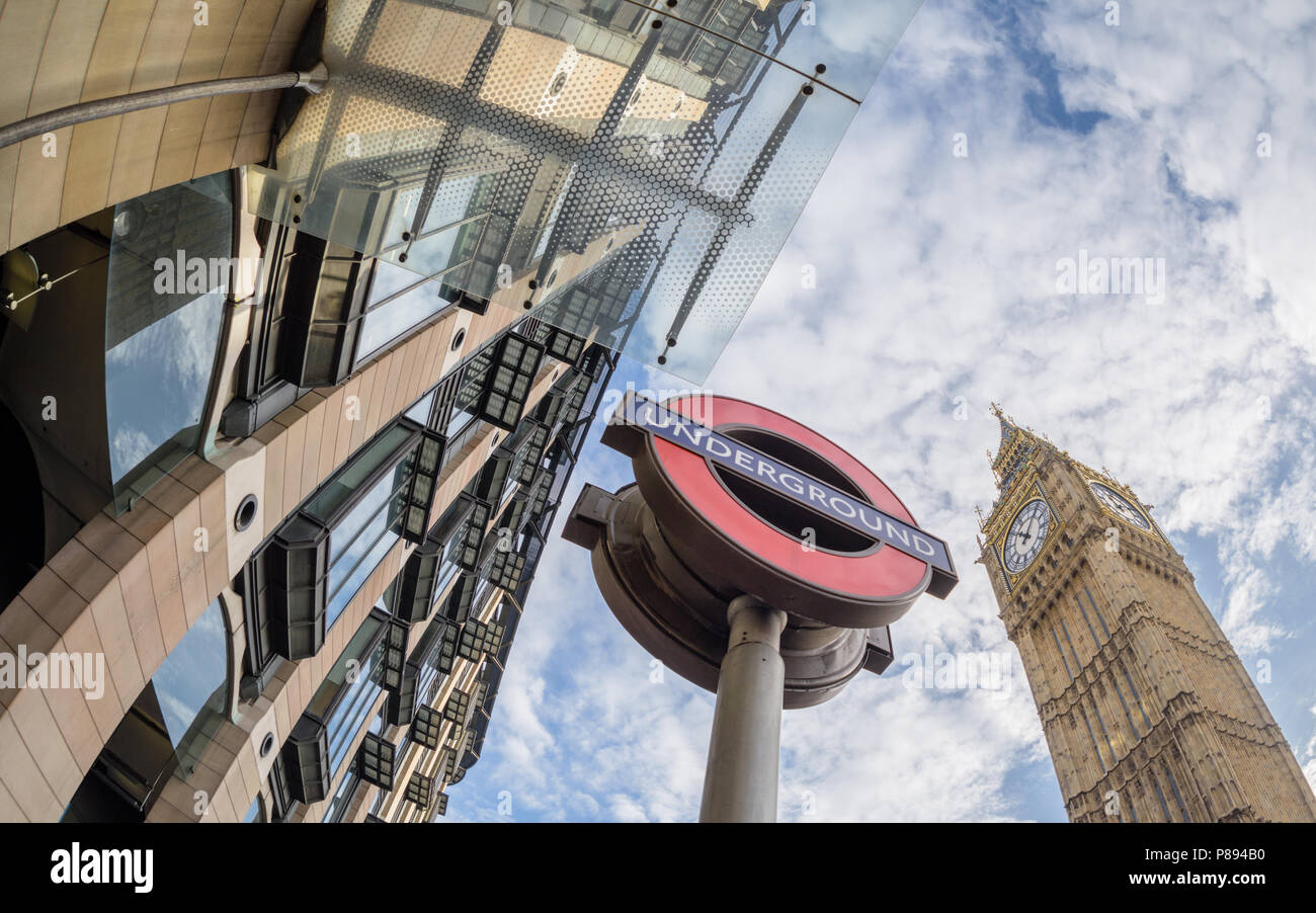 Suchen nach in Westminster Station und der U-Zeichen und Big Ben in London vor einem blauen Himmel mit Wolken mit einem Weitwinkel Objektiv aufgenommen Stockfoto