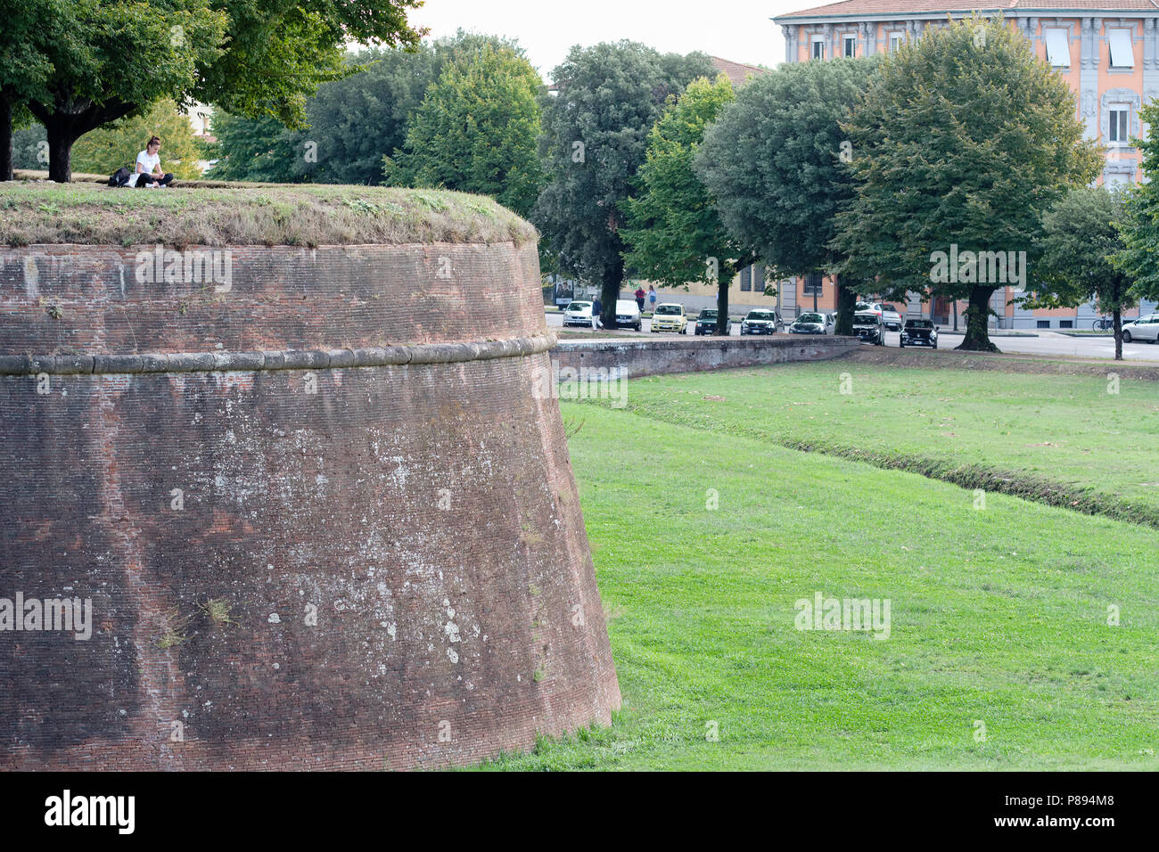 Junge Dame saß oben auf der alten Stadtmauer das Hören von Musik auf Ihr Smartphone, Lucca, Toskana, Italien, Europa, Stockfoto