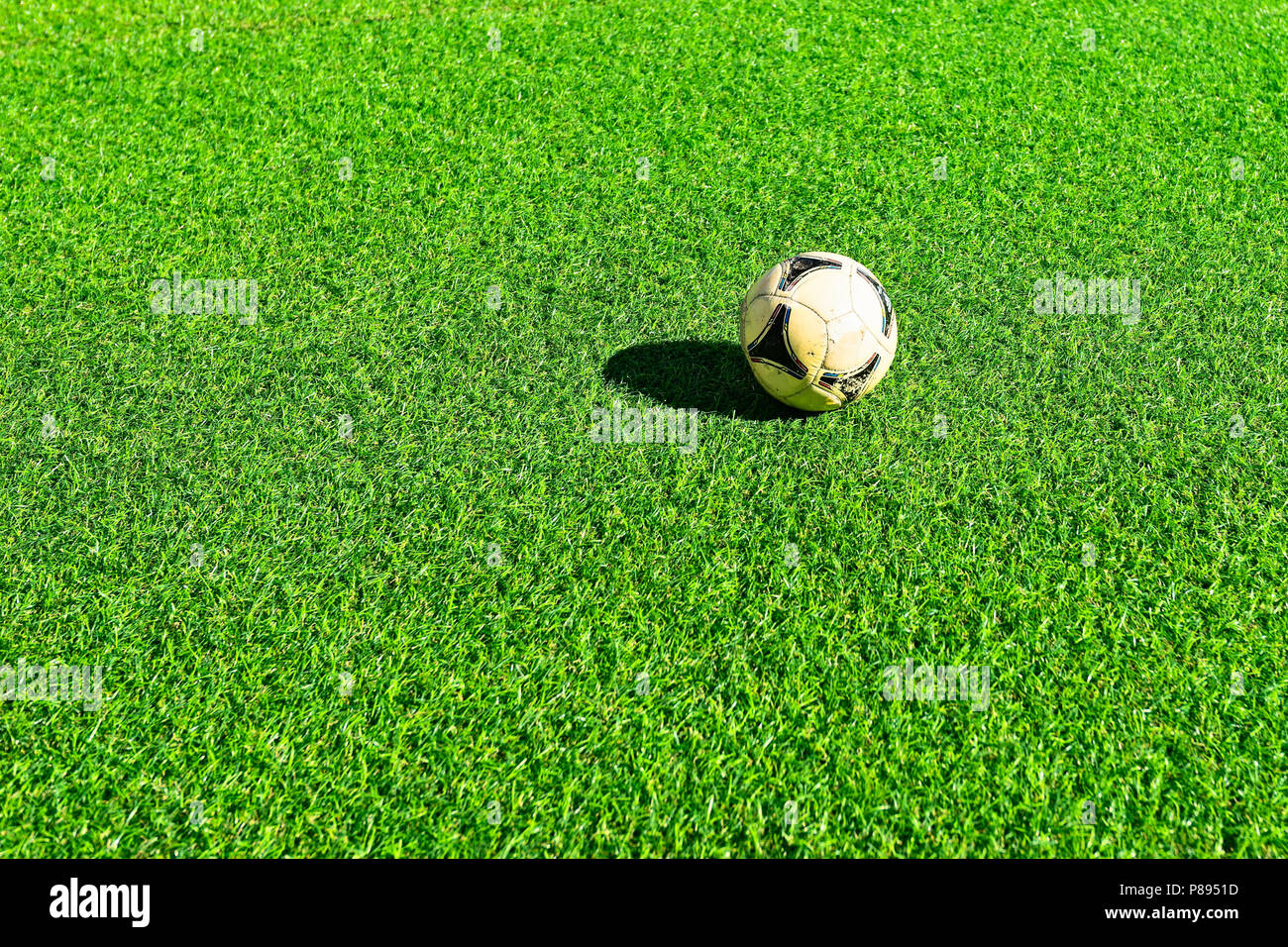 Alte, gebrauchte Fußball-Ball auf der sonnenbeschienenen Kunstrasen oder  Gras der grünen Farbe. Freier Platz für die Eingabe von Text  Stockfotografie - Alamy