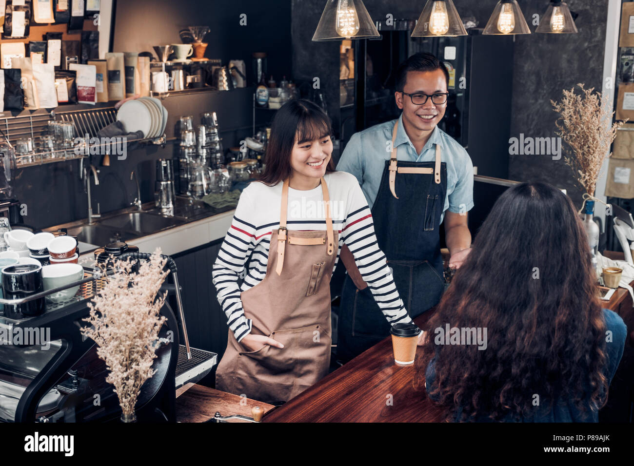 Asien barista Kellner und Kellnerinnen um von Kunden im Coffee Shop, zwei cafe Besitzer schreiben Drink an der Bar, Essen und Trinken Business Con Stockfoto