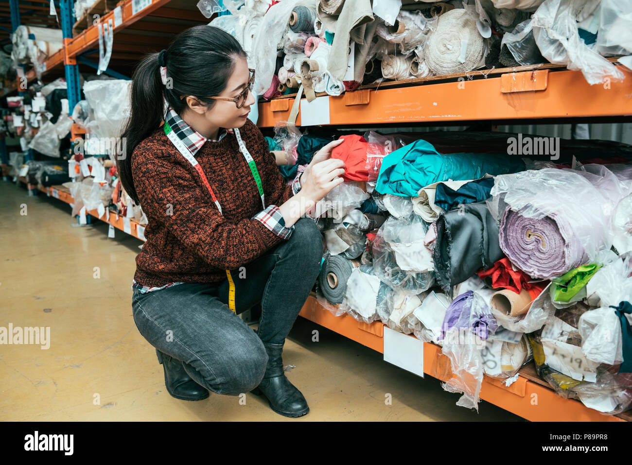 Asiatische Frau manager kniete und suchen die fehlende Textur. Sie ist zeigen und berühren, um sicherzustellen, dass das Material korrekt ist. Stockfoto