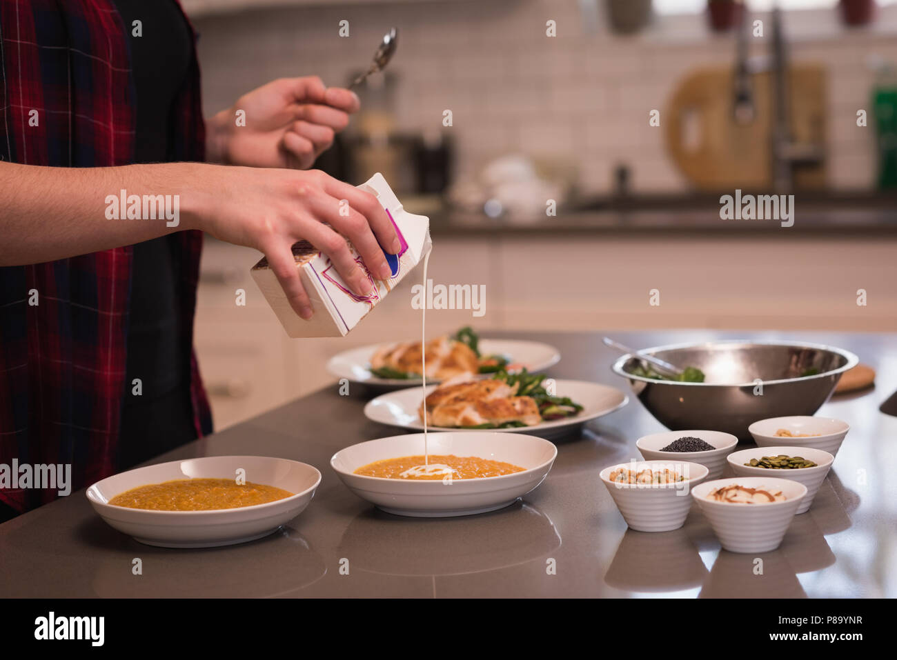 Frau gießen kochen Sahne in Dal zu Hause Stockfoto