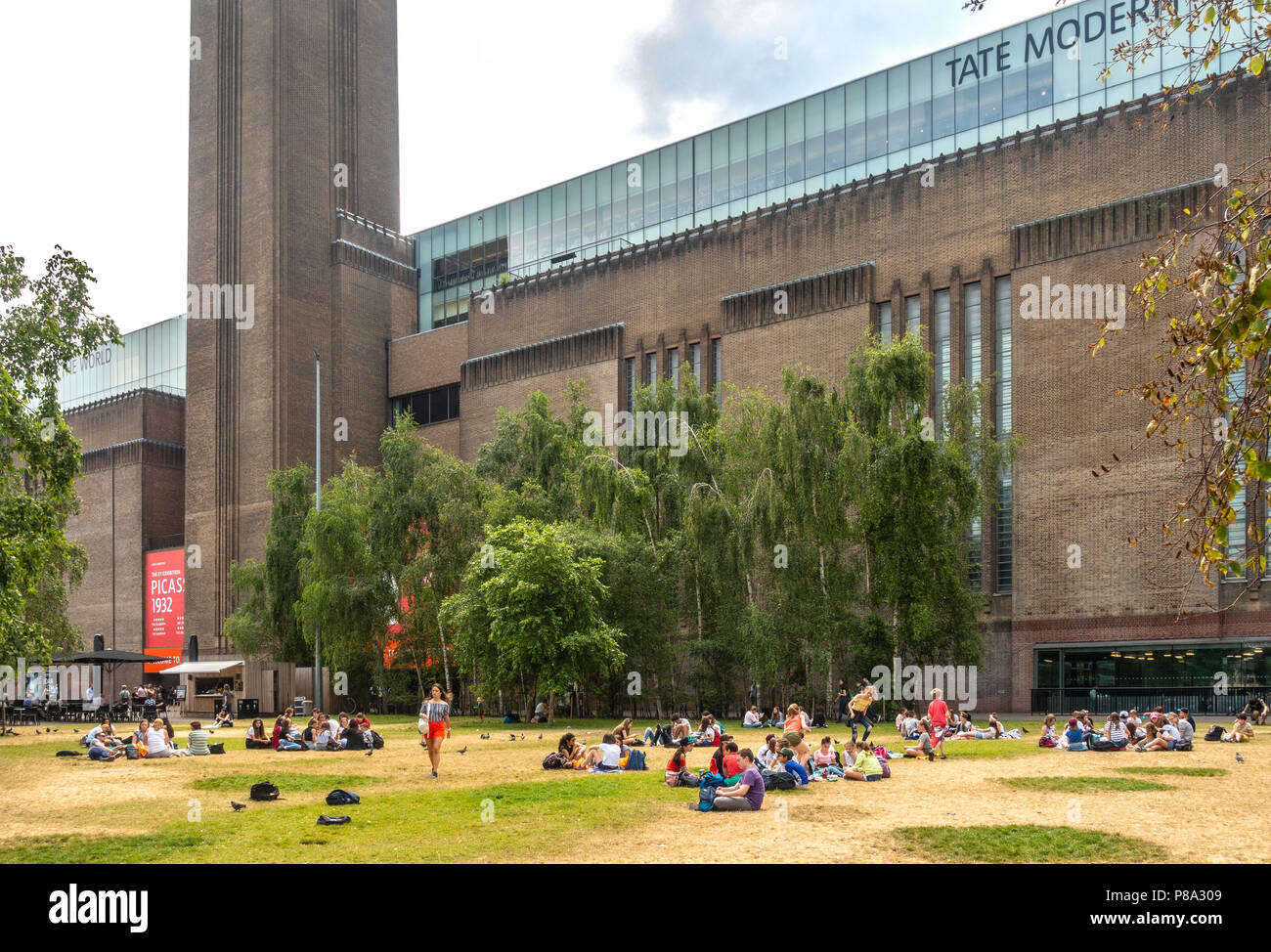 Gruppen von Menschen, vor allem Kinder und Jugendliche, entspannend und Picknick auf dem Rasen außerhalb der Tate Modern Bankside, London, England, Großbritannien Stockfoto