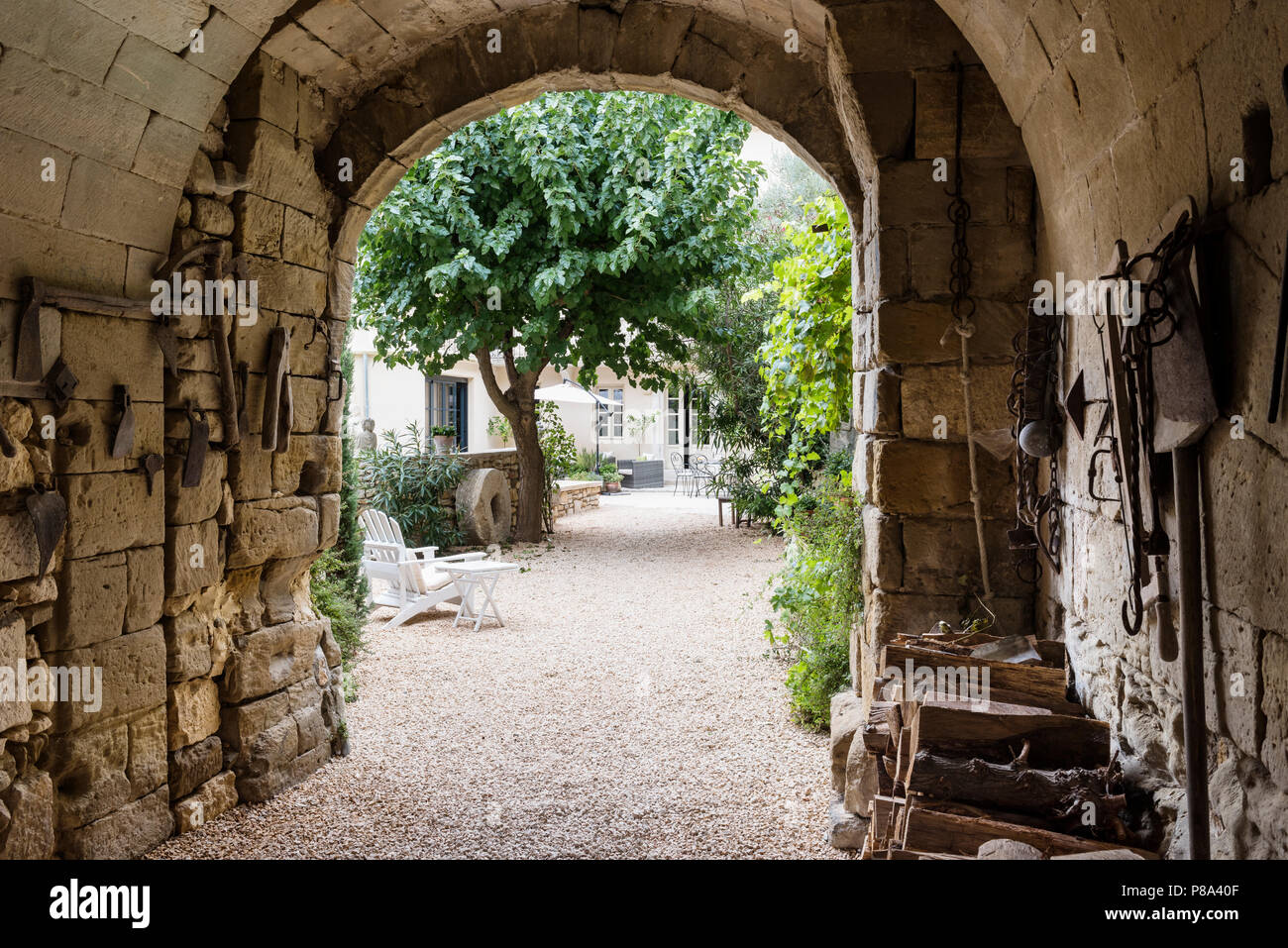 Stone Arch Eingang weg ist mit alten landwirtschaftlichen Werkzeuge, die von den vorherigen Besitzer aufgehängt. Stockfoto