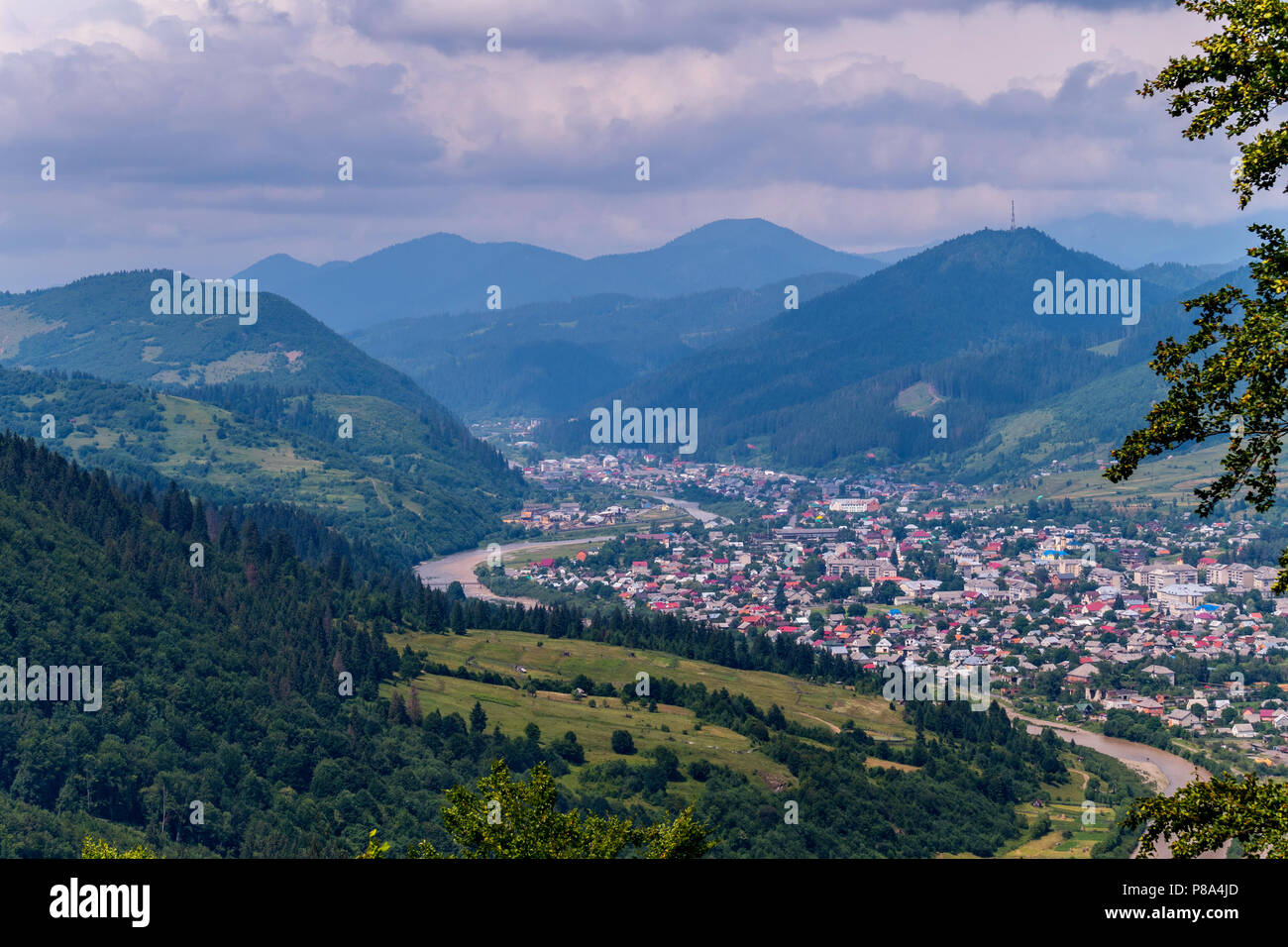 Die blauen Spitzen der Berge im Nebel, die unruhige Himmel in die Wolken und eine kleine Stadt mit einstöckigen Häusern. Für ihr Design Stockfoto