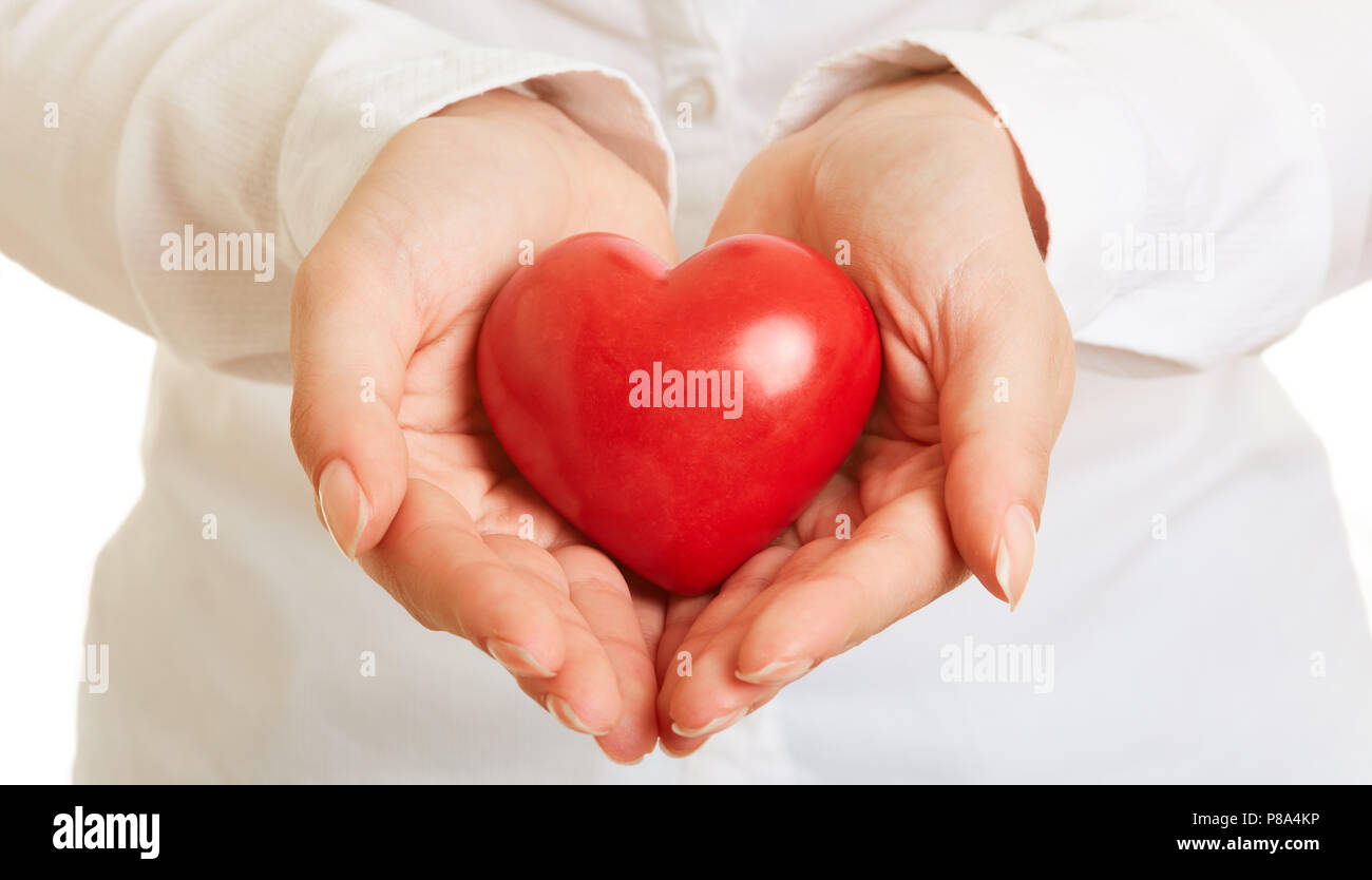 Zwei weibliche Hände halten ein rotes Herz als Health Care Konzept Stockfoto