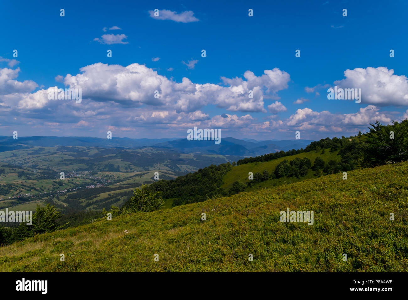 Einen malerischen Blick von der grünen Hang zu Häuser in einem Bergtal von fern liegend erscheinen kleine weiße Punkte. . Für ihr Design Stockfoto
