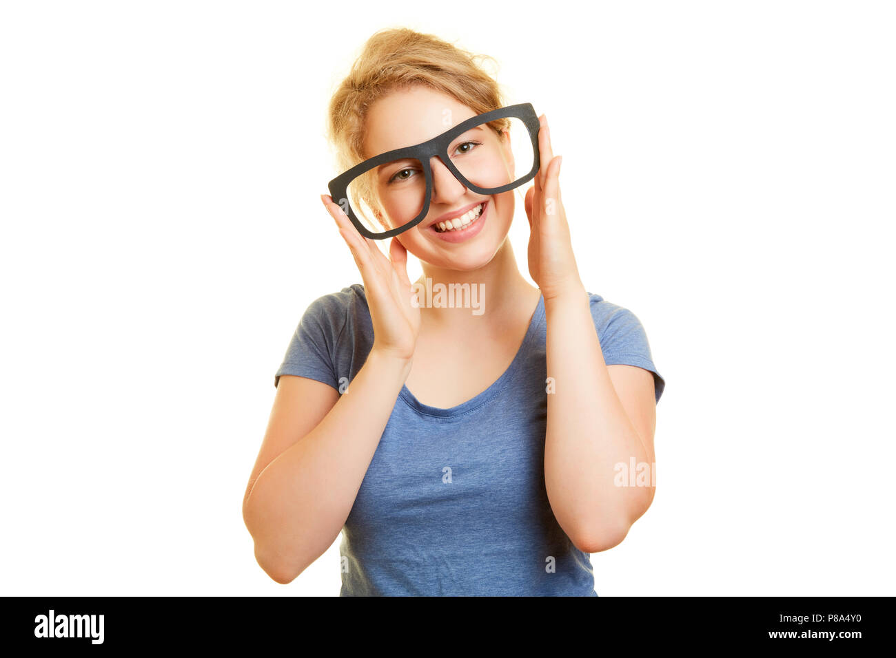 Lächelnde junge Frau hält große Gläser wie ein Dummy, der vor ihren Augen Stockfoto