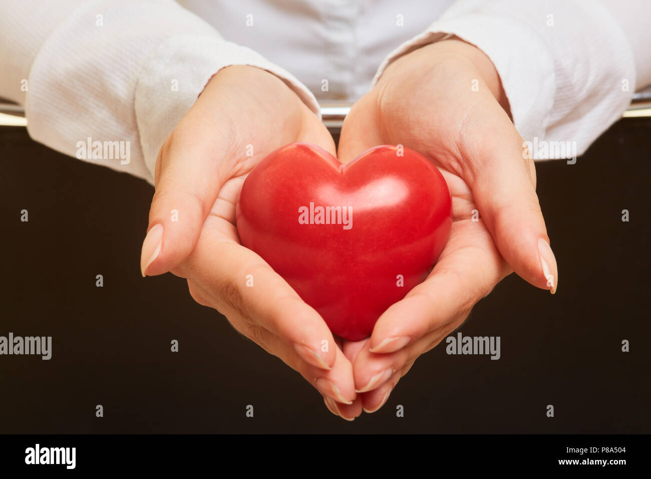 Hände halten roten Herzen als Symbol für Pflege und Gesundheit Vorsorge Stockfoto