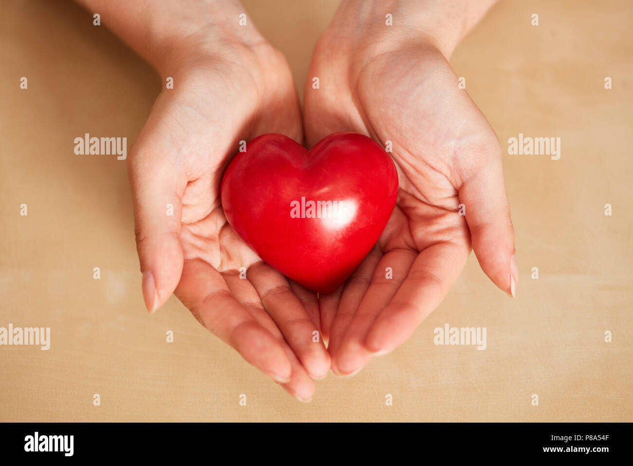 Frau hält Rotes Herz in den Händen als Pflege und Betreuung Konzept Stockfoto