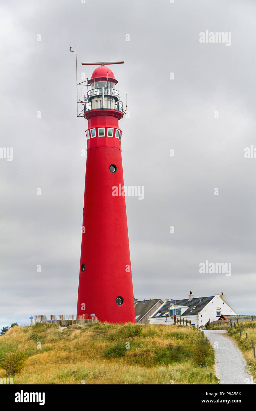 Rote Leuchtturm in den Dünen der holländischen Insel Schiermonnikoog, neben dem Weißen Haus des Leuchtturmwärters Stockfoto