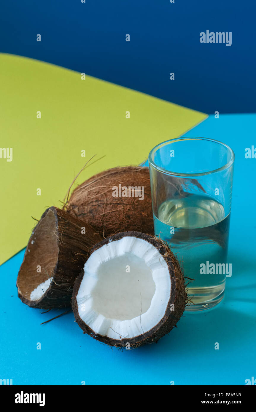 Kokosnuss Wasser, ganze Kokosnüsse auf einer Duo Tone Hintergrund. Kokosnuss Produkte Konzept. Stockfoto