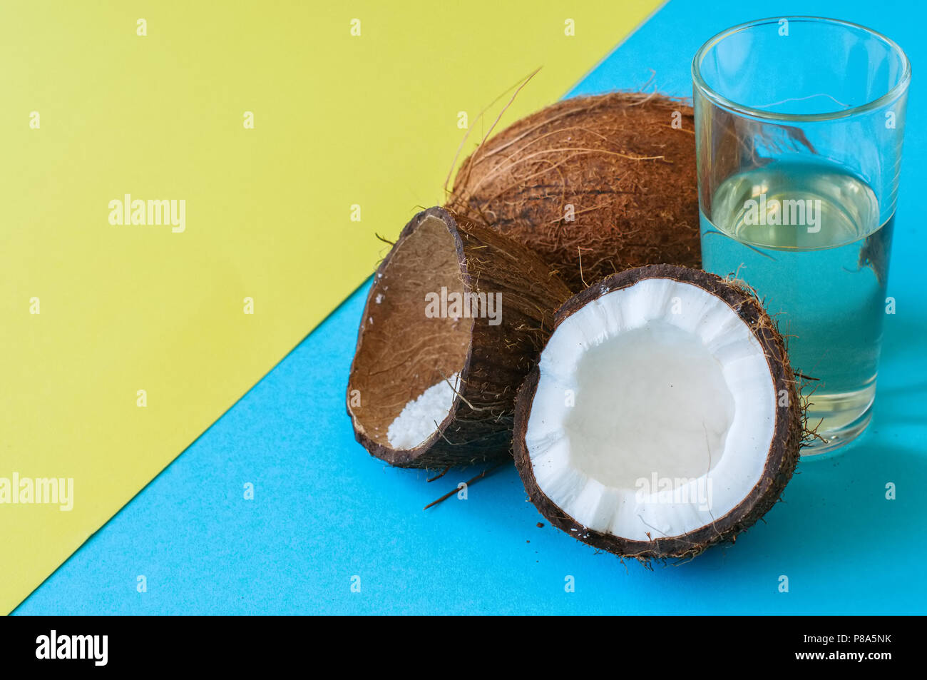 Kokosnuss Wasser, ganze Kokosnüsse auf einer Duo Tone Hintergrund. Kokosnuss Produkte Konzept. Stockfoto