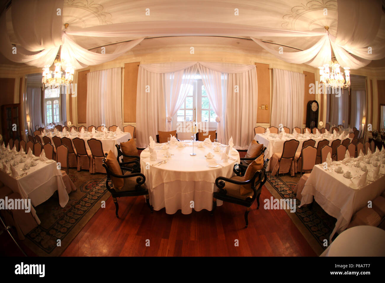 Platz Layout einer Hochzeit Braut mit dem runden Tisch in der Mitte eines kolonialen Raum mit weißen transparente Decke Vorhängen, weißen Tischdecken und ... Stockfoto