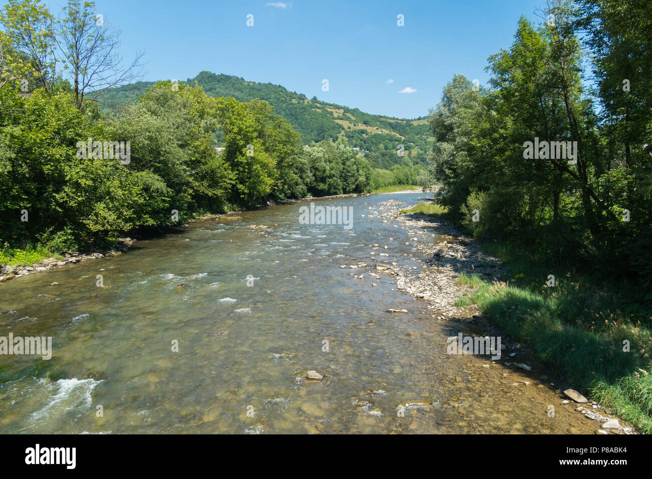 Ein Berg seichten Fluss mit klarem Wasser und einer unteren gefüllt mit Steinen unter fließt. Für ihr Design Stockfoto