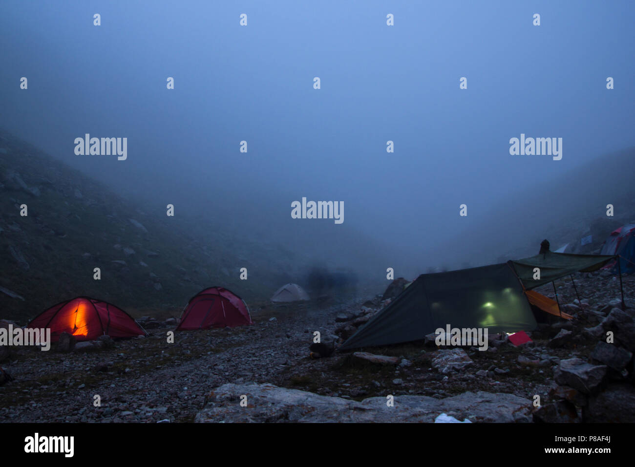 Camping mit Zelt und Touristen in Mountain Valley bei Nacht und Nebel, der Russischen Föderation, dem Kaukasus Stockfoto