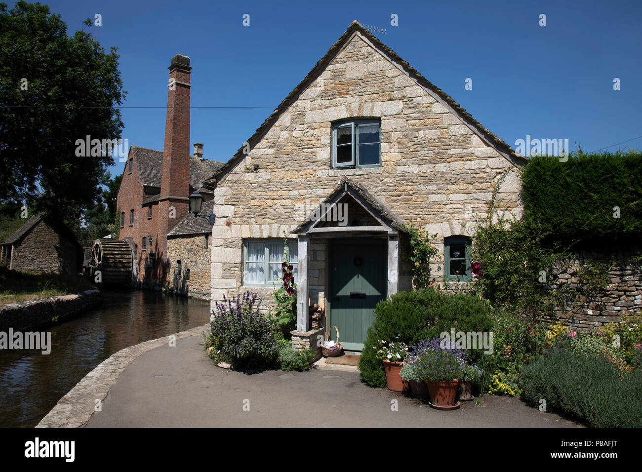 Lower Slaughter in den Cotswolds, Vereinigtes Königreich. Lower Slaughter Dorf liegt an beiden Ufern des Flusses Auge, eine langsame Stream gebaut, durch zwei Stege überquert. Am westlichen Ende des Dorfes gibt es eine aus dem 19. Jahrhundert Wassermühle mit einem undershot-waterwheel und ein Kamin für zusätzliche Dampfleistung. Während die Mühle ist aus rotem Backstein die meisten der 16. und 17. Jahrhunderts Häuser im Dorf verwenden Cotswold Stein gebaut. Der Name des Dorfes leitet sich nass Lough des alten englischen Begriff "Sinn 'Land'. Die Cotswolds sind ein Bereich, in South Central England. Der Bereich wird durch das Fundament der Kalkstein definiert Stockfoto