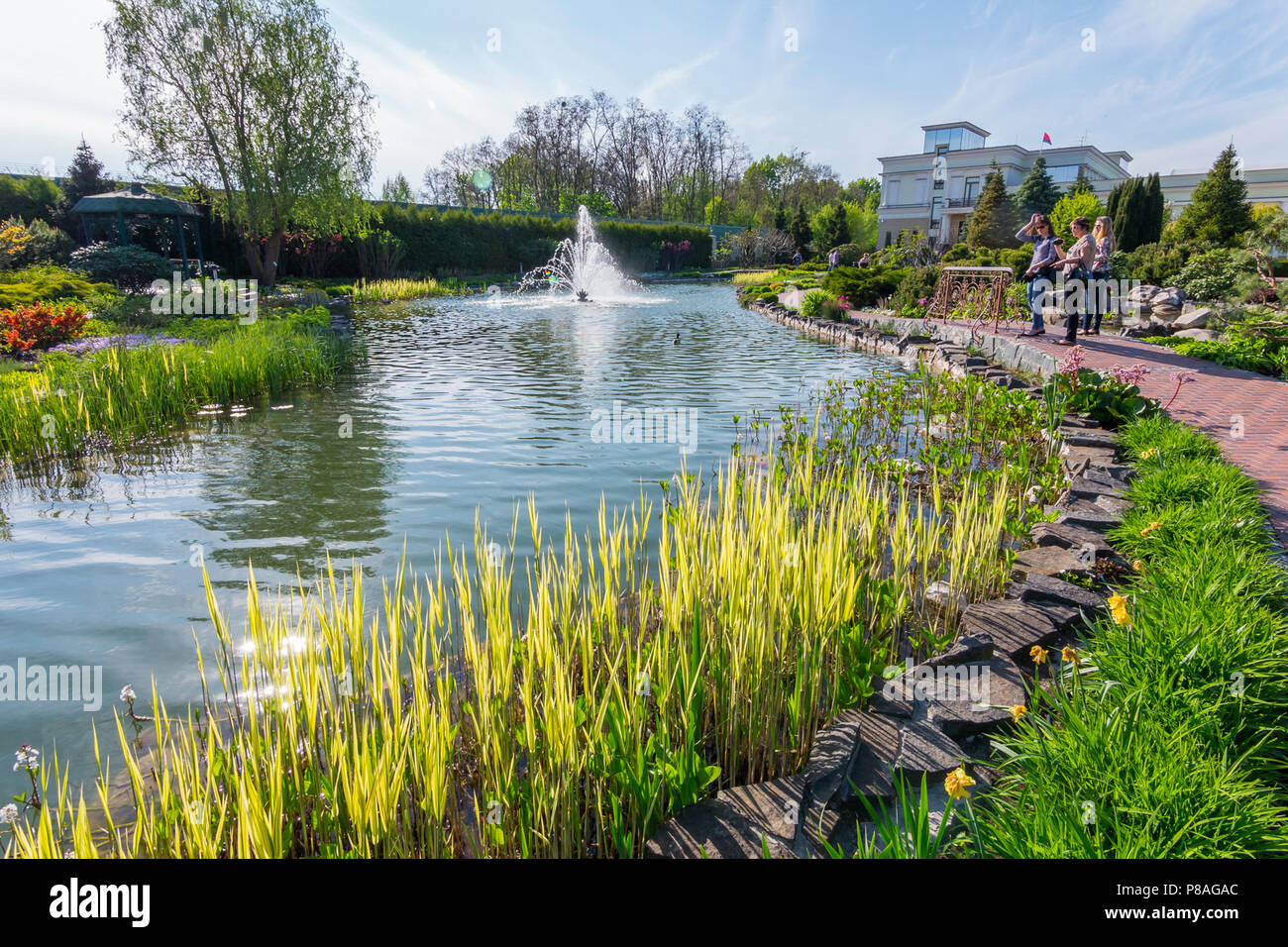 Touristen im Park Blick auf den Teich mit einem schönen Brunnen und Steine mit einem Muster am Rand der Ufer gesäumt. . Für ihr Design Stockfoto