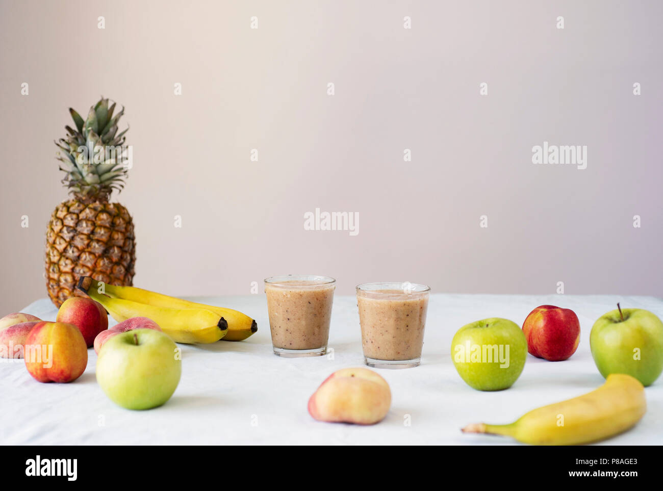 Gesunde Rohstoffe veganes Essen kochen Hintergrund. Frische Früchte und Smoothies am Tisch über weiße Tischtuch. Sauber Essen, basische Ernährung Konzept Stockfoto